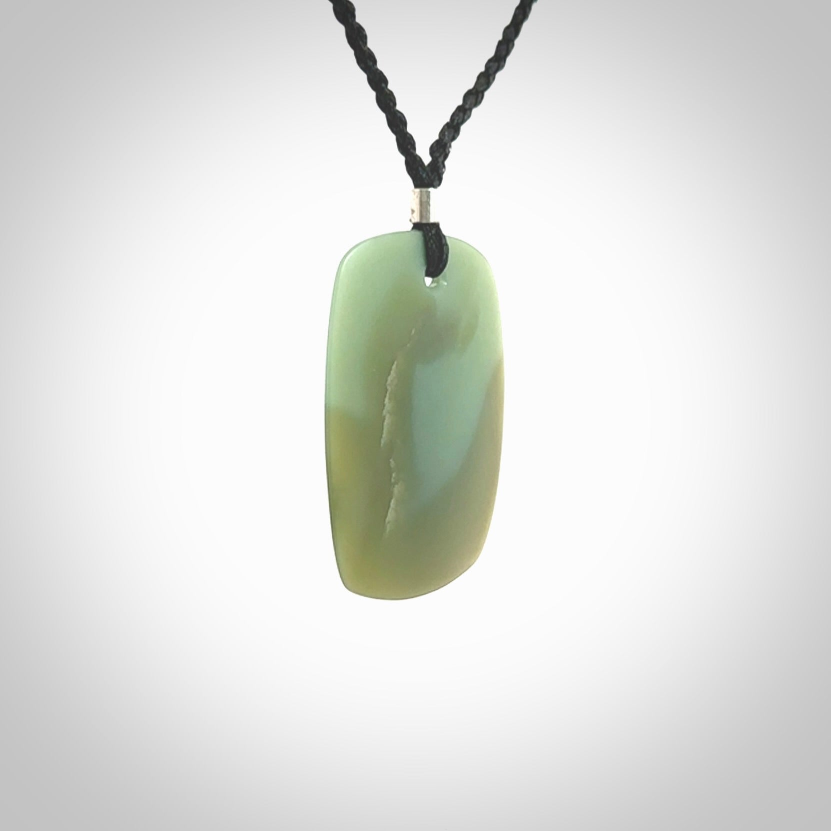 This is a Inanga Jade contemporary Drop pendant carved here in New Zealand by Josey Coyle. It is carved from a piece of rare New Zealand Inanga Pounamu, Jade. The jade is a subtle blue/green colour. A very finely carved pendant with an adjustable black cord.