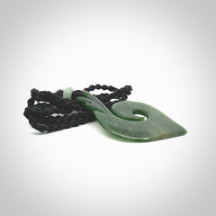 This photo shows a beautiful jade swan hook suspended from a hand plaited black cord. This swan hook was carved for us by Jen Hung who is a master jade carver from New Zealand.