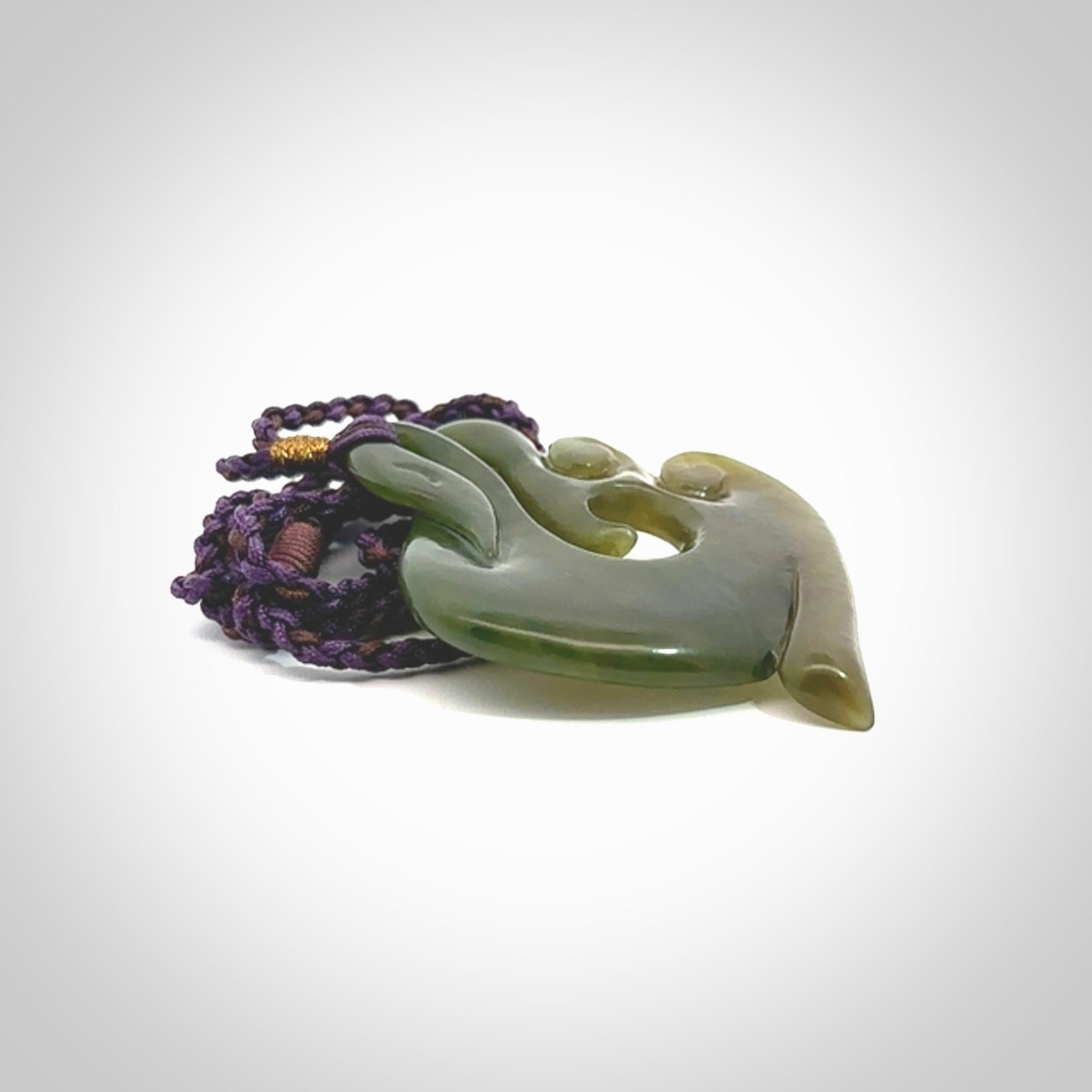 This photo shows a beautiful jade swan hook suspended from a hand plaited purple/brown cord. This swan hook was carved for us by Jen Hung who is a master jade carver from New Zealand.