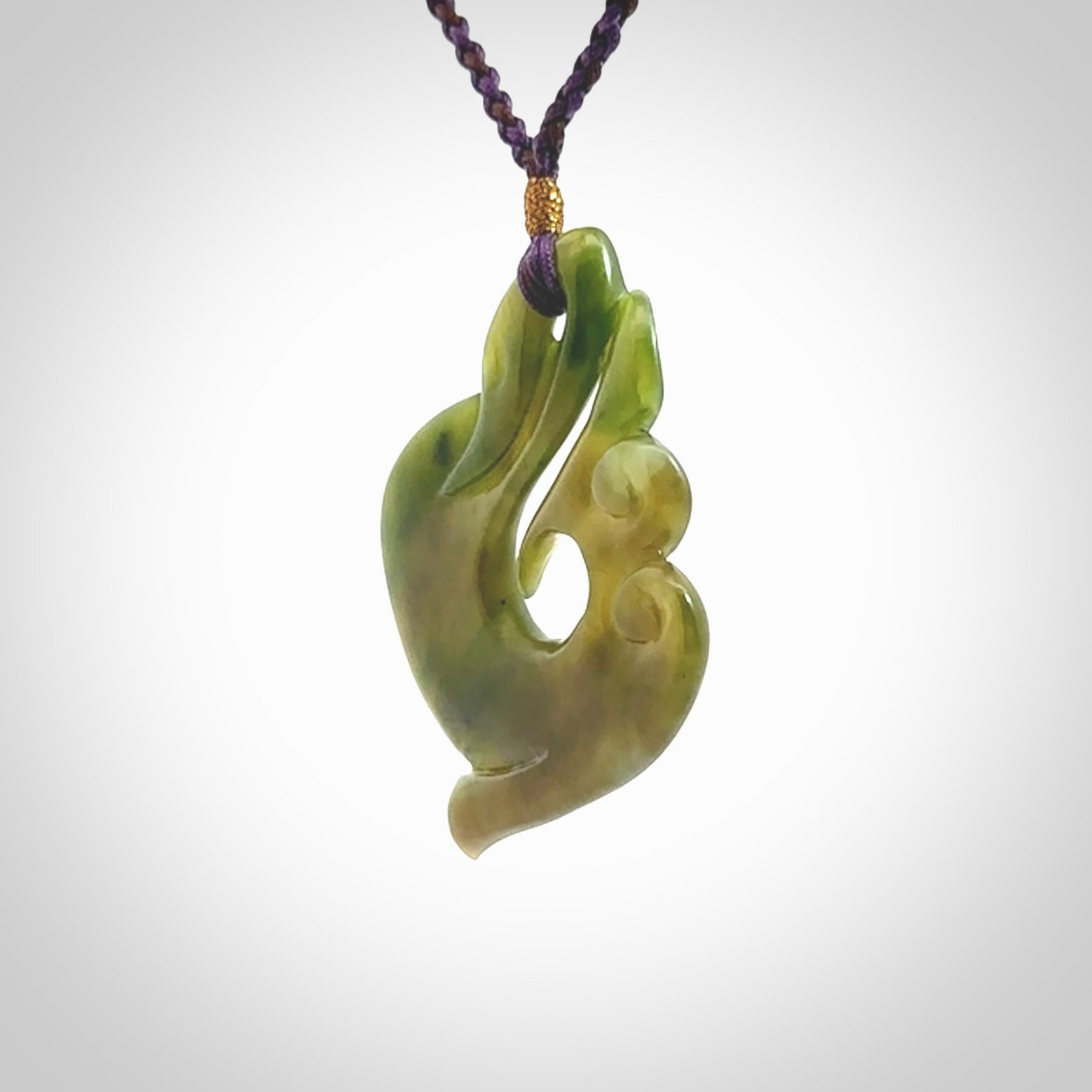 This photo shows a beautiful jade swan hook suspended from a hand plaited purple/brown cord. This swan hook was carved for us by Jen Hung who is a master jade carver from New Zealand.