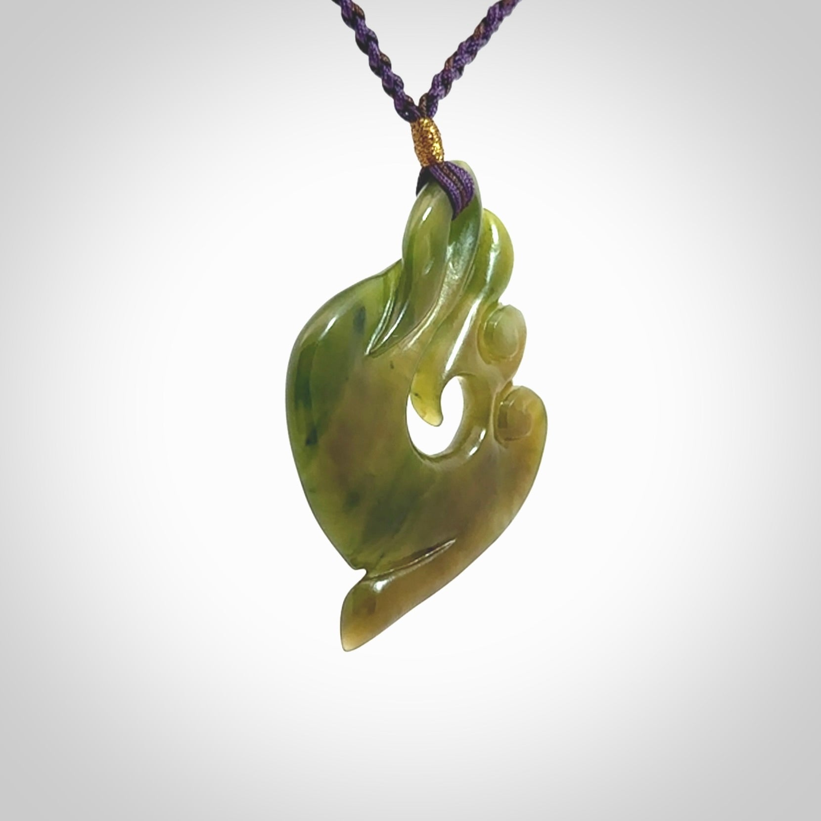 This photo shows a beautiful jade swan hook suspended from a hand plaited purple/brown cord. This swan hook was carved for us by Jen Hung who is a master jade carver from New Zealand.