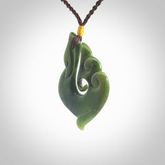 This photo shows a beautiful jade swan hook suspended from a hand plaited brown cord. This swan hook was carved for us by Jen Hung who is a master jade carver from New Zealand.