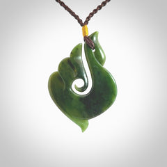 This photo shows a beautiful jade swan hook suspended from a hand plaited brown cord. This swan hook was carved for us by Jen Hung who is a master jade carver from New Zealand.