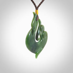 This photo shows a beautiful jade swan hook suspended from a hand plaited brown cord. This swan hook was carved for us by Jen Hung who is a master jade carver from New Zealand.