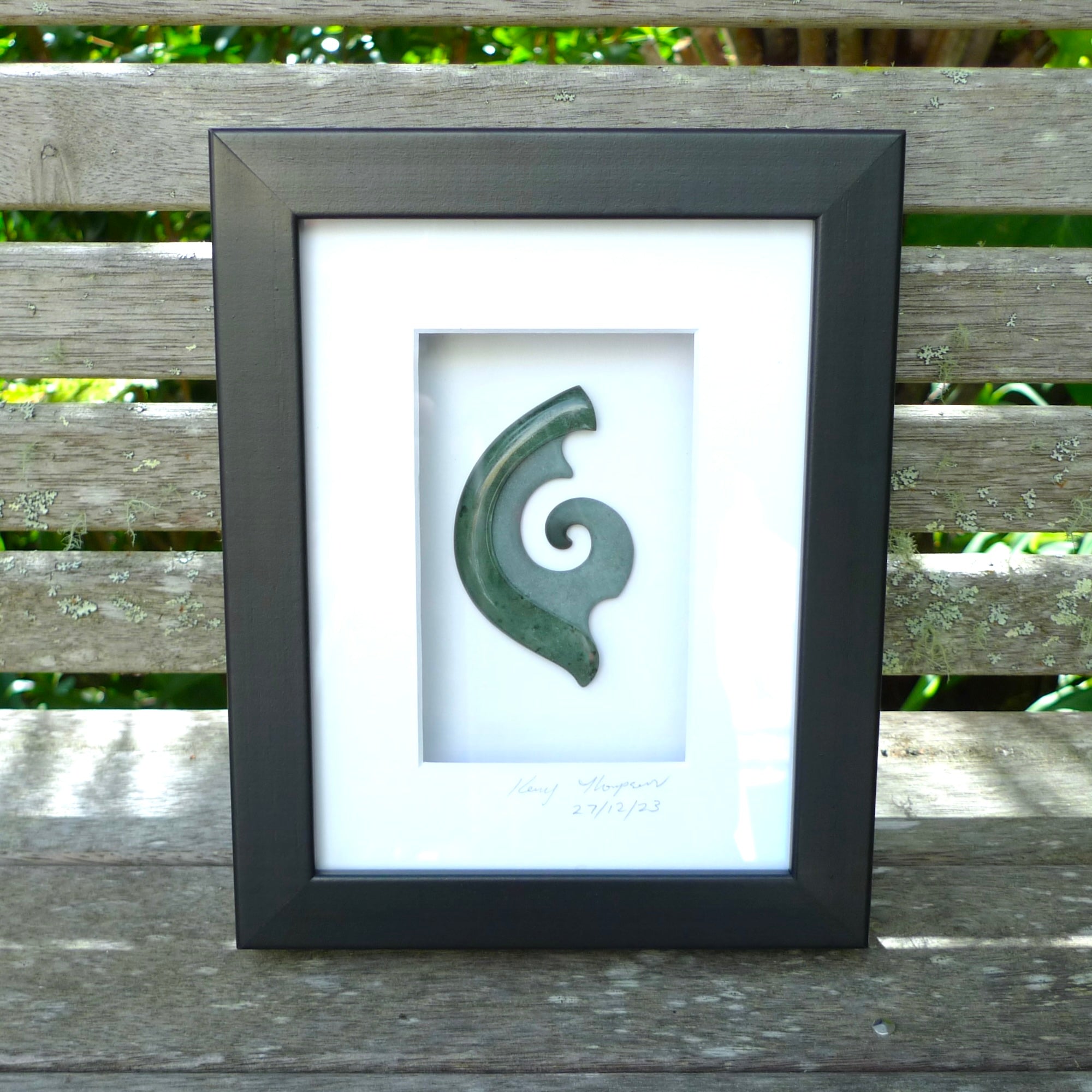 A hand carved large New Zealand Jade Koru necklace that has been framed and signed by artist Kerry Thompson. A large sized hand made koru necklace by New Zealand artist Kerry Thompson. One off framed work of art to wear. Delivered with Express Courier.