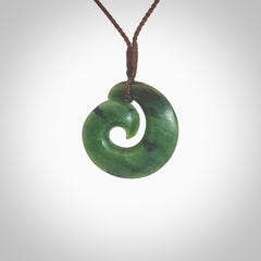 This picture shows a koru pendant, hand carved from New Zealand jade. We will provide this with an adjustable plaited cord. This has been hand carved by Kyohei Noguchi. One only pendant, shipped to you with express courier.