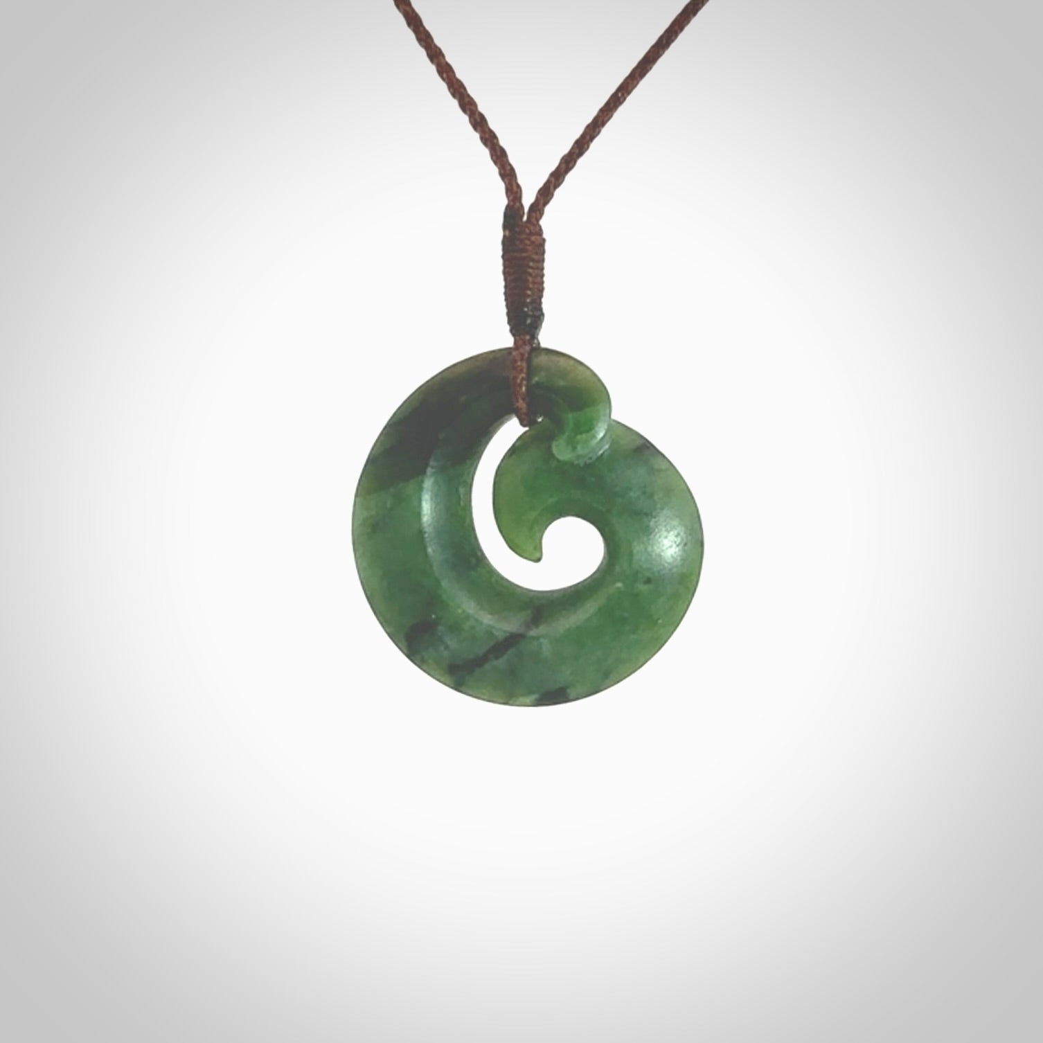 This picture shows a koru pendant, hand carved from New Zealand jade. We will provide this with an adjustable plaited cord. This has been hand carved by Kyohei Noguchi. One only pendant, shipped to you with express courier.