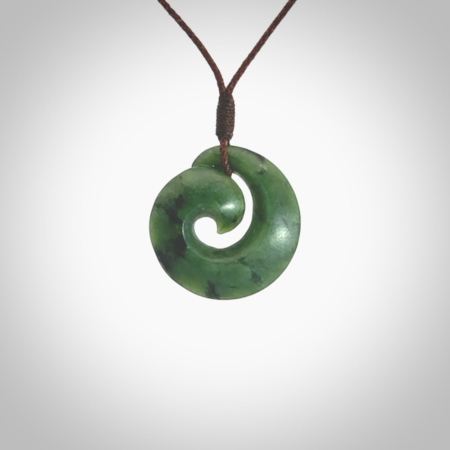 This picture shows a koru pendant, hand carved from New Zealand jade. We will provide this with an adjustable plaited cord. This has been hand carved by Kyohei Noguchi. One only pendant, shipped to you with express courier.