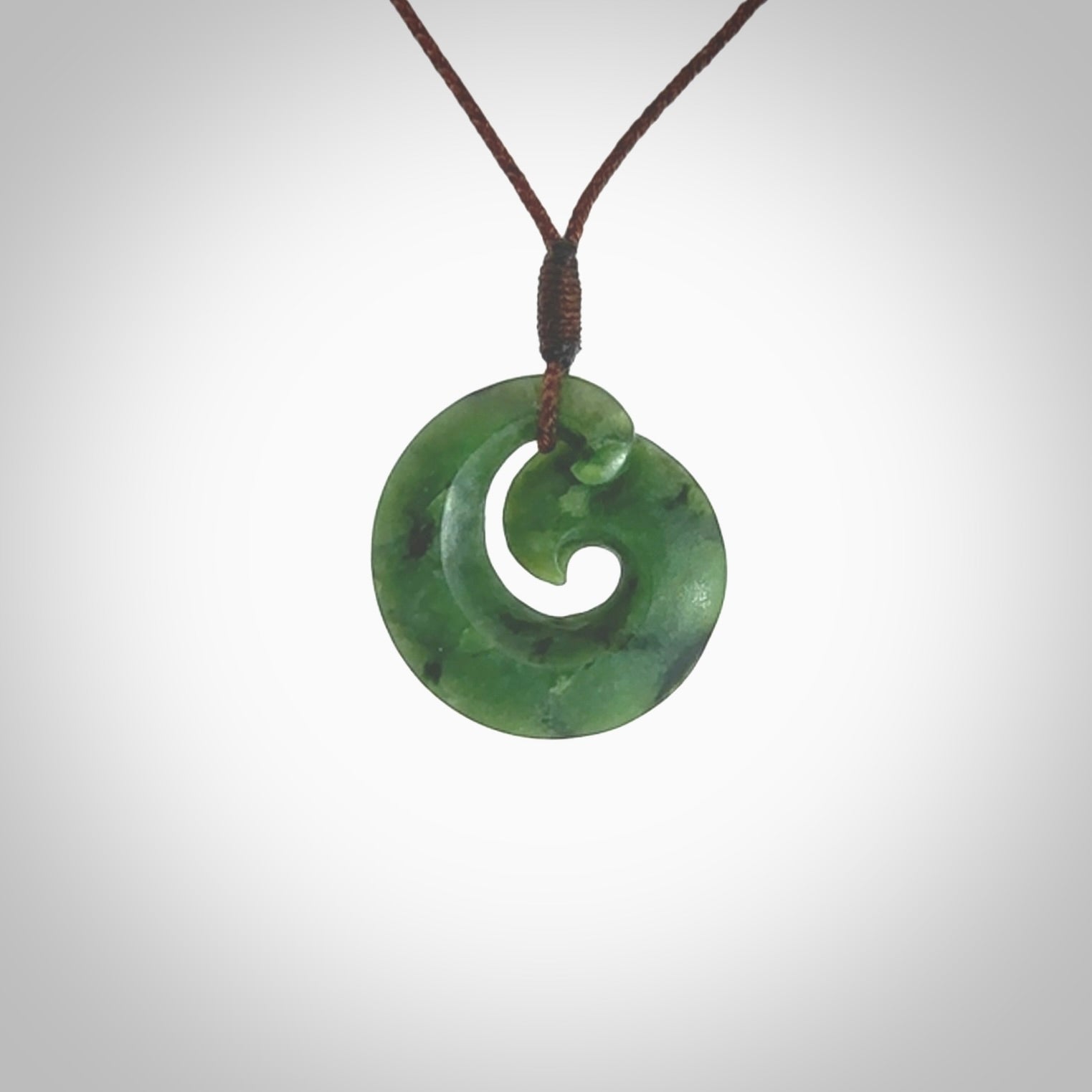 This picture shows a koru pendant, hand carved from New Zealand jade. We will provide this with an adjustable plaited cord. This has been hand carved by Kyohei Noguchi. One only pendant, shipped to you with express courier.