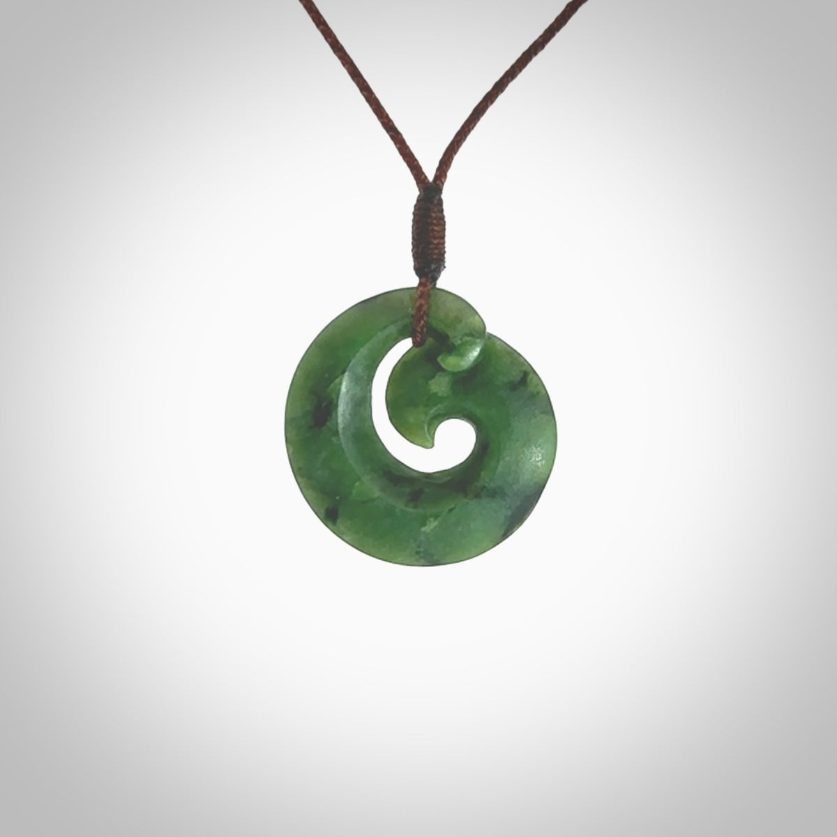 This picture shows a koru pendant, hand carved from New Zealand jade. We will provide this with an adjustable plaited cord. This has been hand carved by Kyohei Noguchi. One only pendant, shipped to you with express courier.