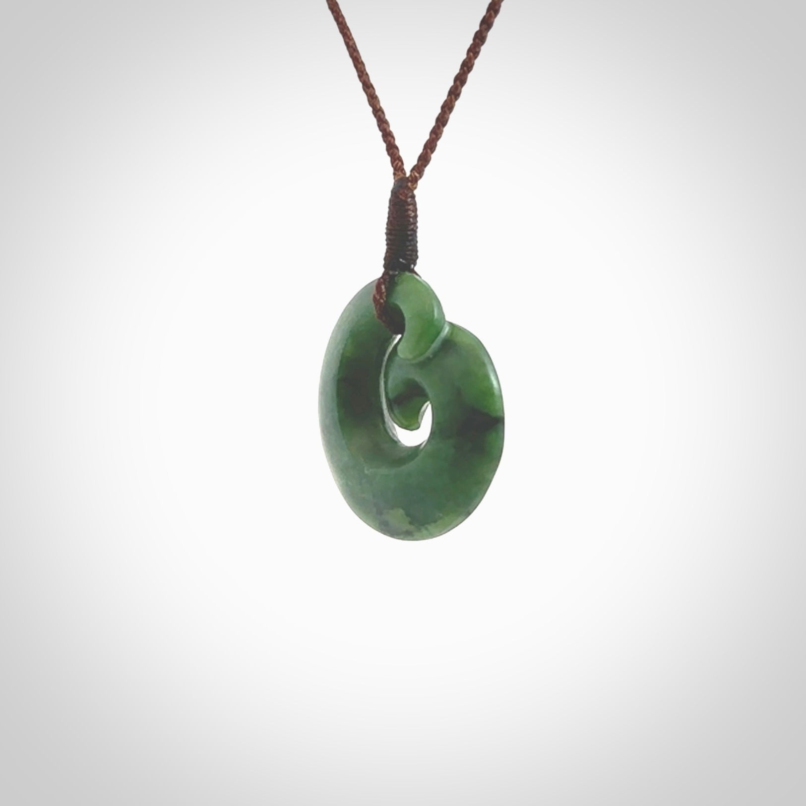 This picture shows a koru pendant, hand carved from New Zealand jade. We will provide this with an adjustable plaited cord. This has been hand carved by Kyohei Noguchi. One only pendant, shipped to you with express courier.