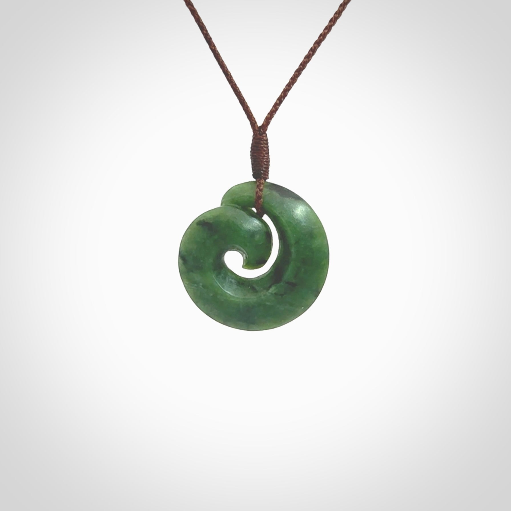 This picture shows a koru pendant, hand carved from New Zealand jade. We will provide this with an adjustable plaited cord. This has been hand carved by Kyohei Noguchi. One only pendant, shipped to you with express courier.