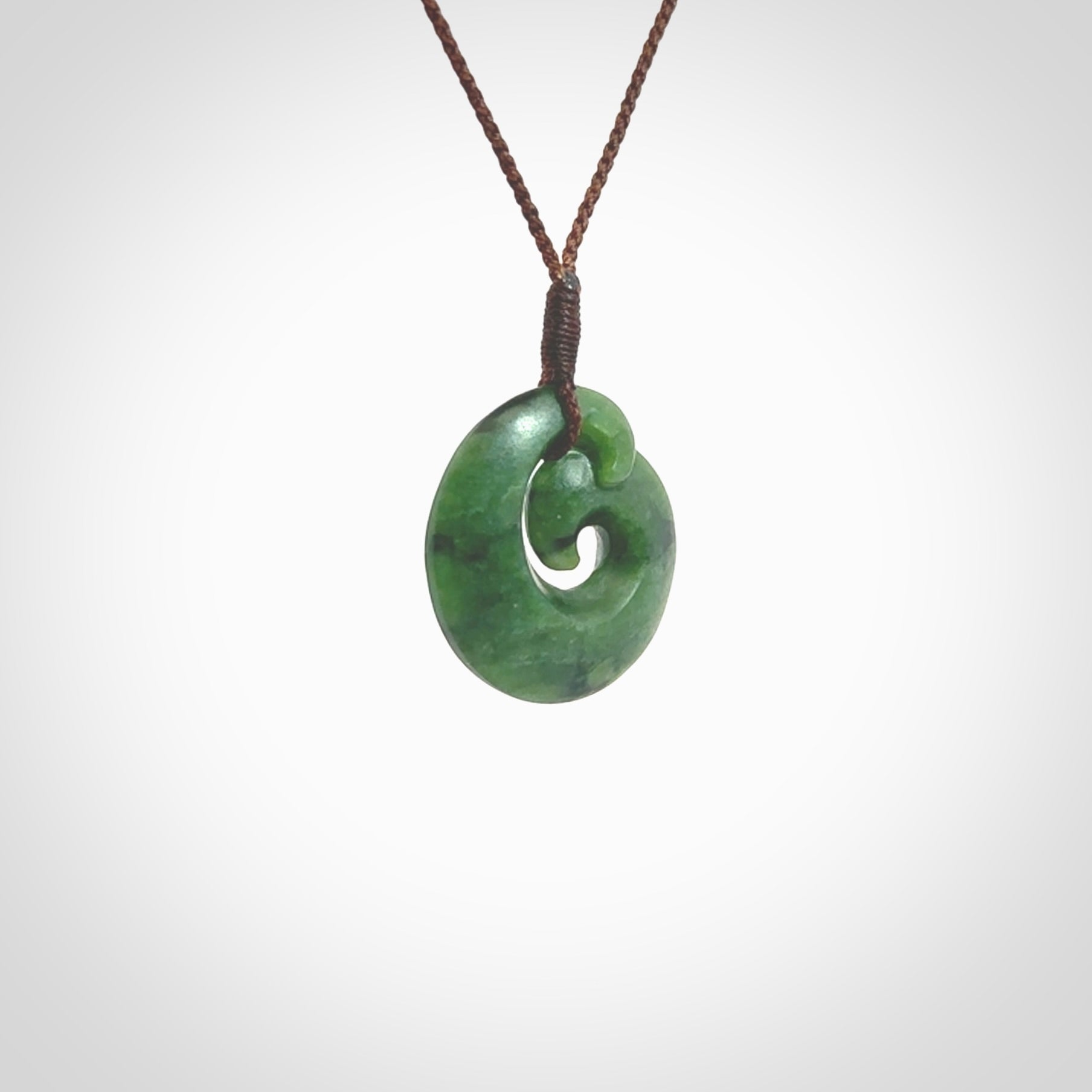 This picture shows a koru pendant, hand carved from New Zealand jade. We will provide this with an adjustable plaited cord. This has been hand carved by Kyohei Noguchi. One only pendant, shipped to you with express courier.