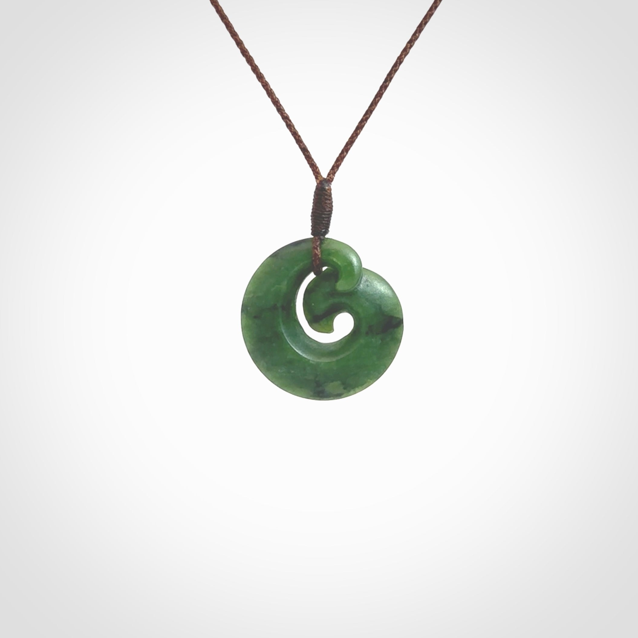 This picture shows a koru pendant, hand carved from New Zealand jade. We will provide this with an adjustable plaited cord. This has been hand carved by Kyohei Noguchi. One only pendant, shipped to you with express courier.