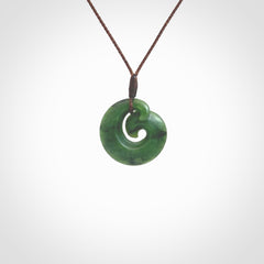 This picture shows a koru pendant, hand carved from New Zealand jade. We will provide this with an adjustable plaited cord. This has been hand carved by Kyohei Noguchi. One only pendant, shipped to you with express courier.