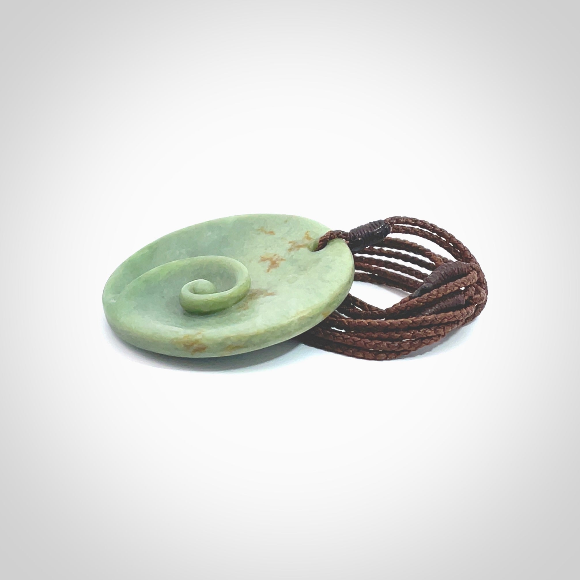 This pendant is a medium sized and cupped koru necklace carved from a lovely light green piece of New Zealand Marsden Flower Jade. Kyohei Noguchi carved this piece for us so the workmanship is outstanding. Handmade in New Zealand, a beautiful piece of jade jewellery. Provided with an adjustable brown cord and packaged in a woven kete pouch.