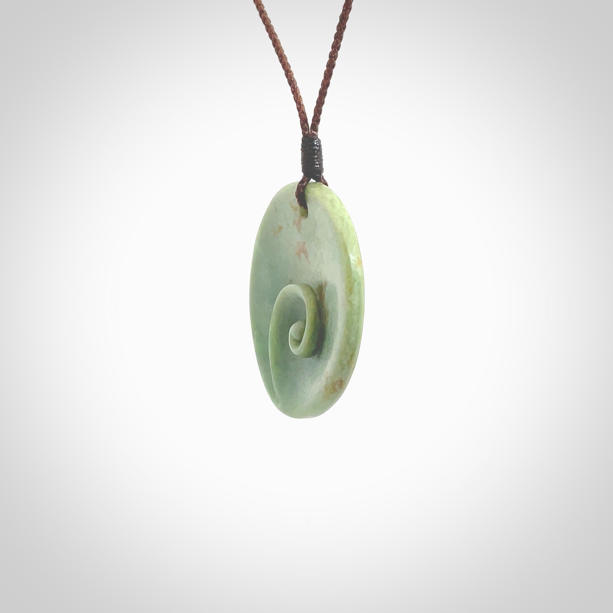 This pendant is a medium sized and cupped koru necklace carved from a lovely light green piece of New Zealand Marsden Flower Jade. Kyohei Noguchi carved this piece for us so the workmanship is outstanding. Handmade in New Zealand, a beautiful piece of jade jewellery. Provided with an adjustable brown cord and packaged in a woven kete pouch.