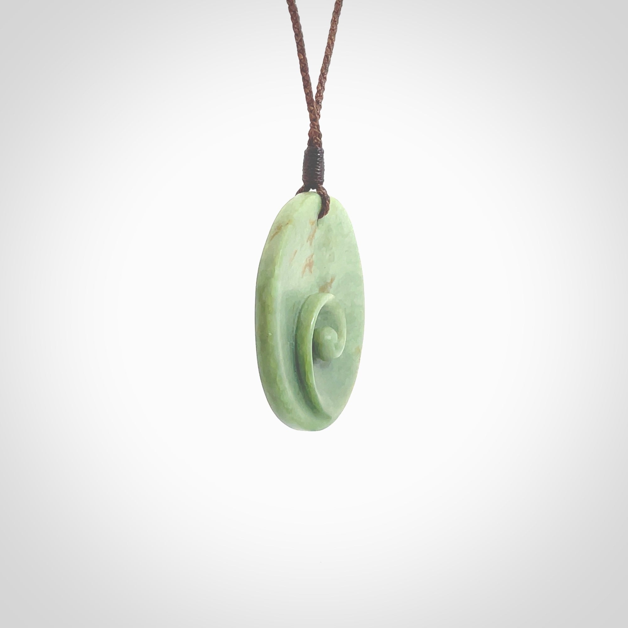 This pendant is a medium sized and cupped koru necklace carved from a lovely light green piece of New Zealand Marsden Flower Jade. Kyohei Noguchi carved this piece for us so the workmanship is outstanding. Handmade in New Zealand, a beautiful piece of jade jewellery. Provided with an adjustable brown cord and packaged in a woven kete pouch.