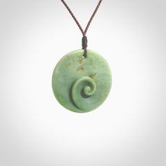 This pendant is a medium sized and cupped koru necklace carved from a lovely light green piece of New Zealand Marsden Flower Jade. Kyohei Noguchi carved this piece for us so the workmanship is outstanding. Handmade in New Zealand, a beautiful piece of jade jewellery. Provided with an adjustable brown cord and packaged in a woven kete pouch.