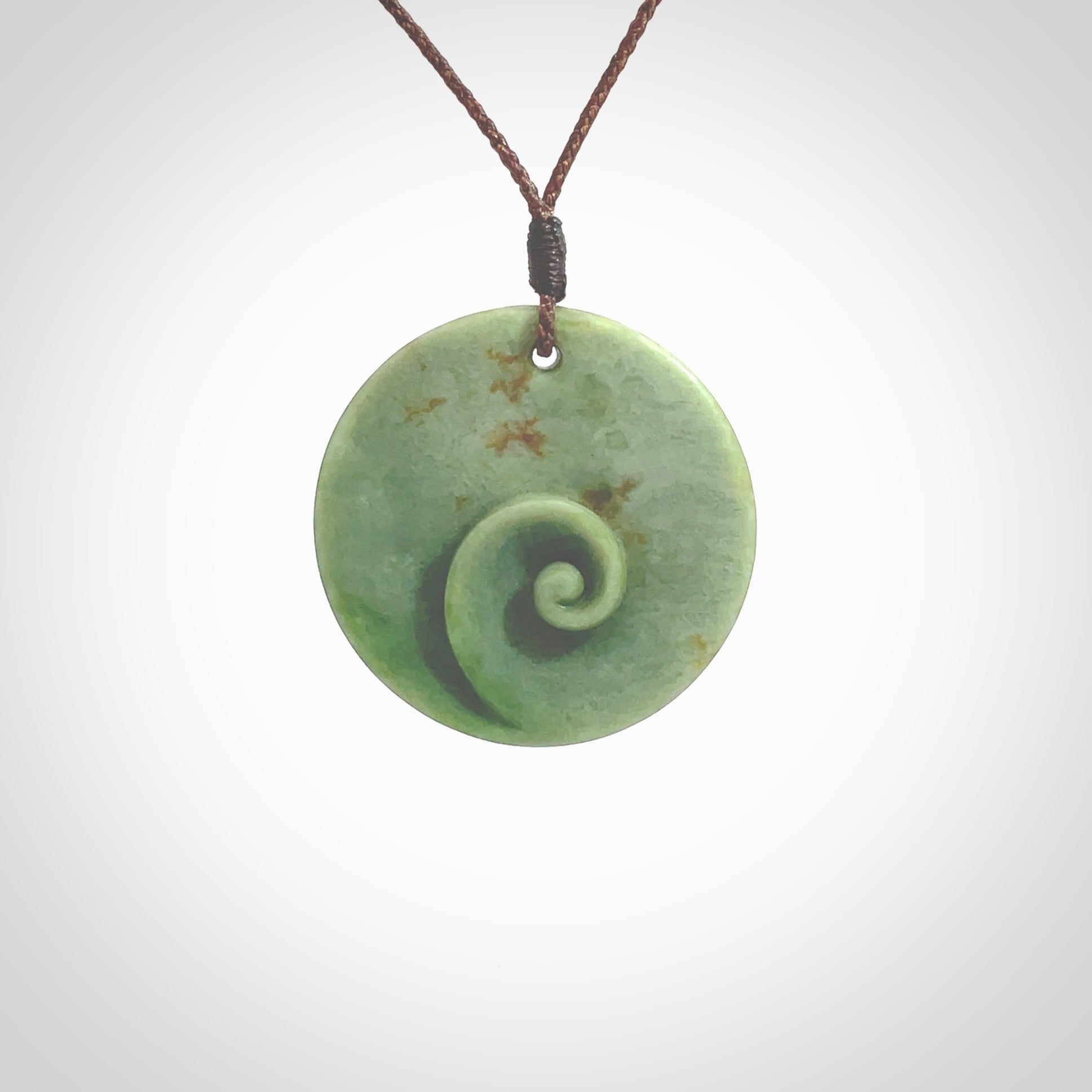 This pendant is a medium sized and cupped koru necklace carved from a lovely light green piece of New Zealand Marsden Flower Jade. Kyohei Noguchi carved this piece for us so the workmanship is outstanding. Handmade in New Zealand, a beautiful piece of jade jewellery. Provided with an adjustable brown cord and packaged in a woven kete pouch.