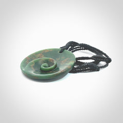 This pendant is a large sized and cupped koru necklace carved from a dark green piece of New Zealand Marsden Flower Jade. Kyohei Noguchi carved this piece for us so the workmanship is outstanding. Handmade in New Zealand, a beautiful piece of jade jewellery. Provided with an adjustable black cord and packaged in a woven kete pouch.