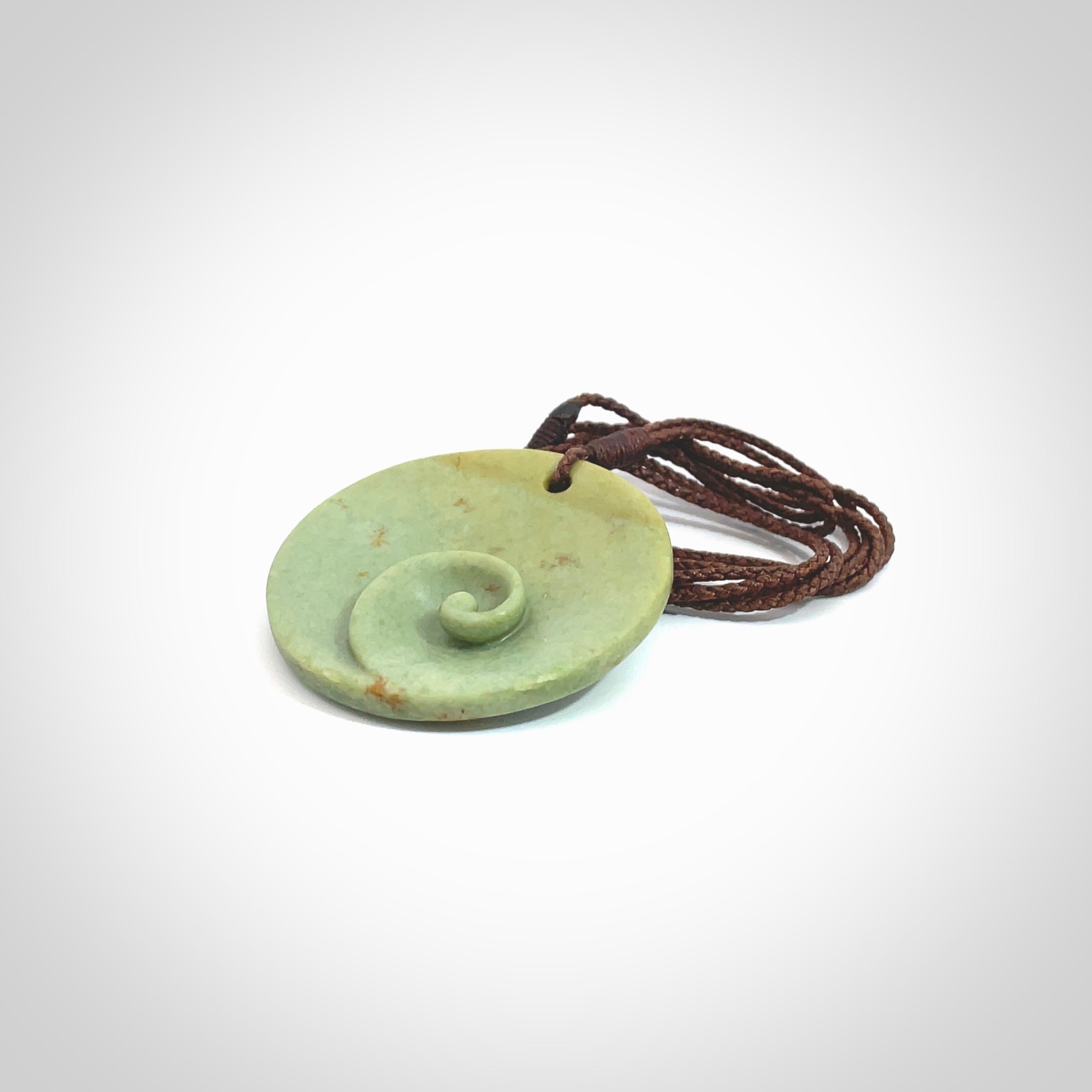 This pendant is a medium sized and cupped koru necklace carved from a lovely light green piece of New Zealand Marsden Flower Jade. Kyohei Noguchi carved this piece for us so the workmanship is outstanding. Handmade in New Zealand, a beautiful piece of jade jewellery. Provided with an adjustable brown cord and packaged in a woven kete pouch.