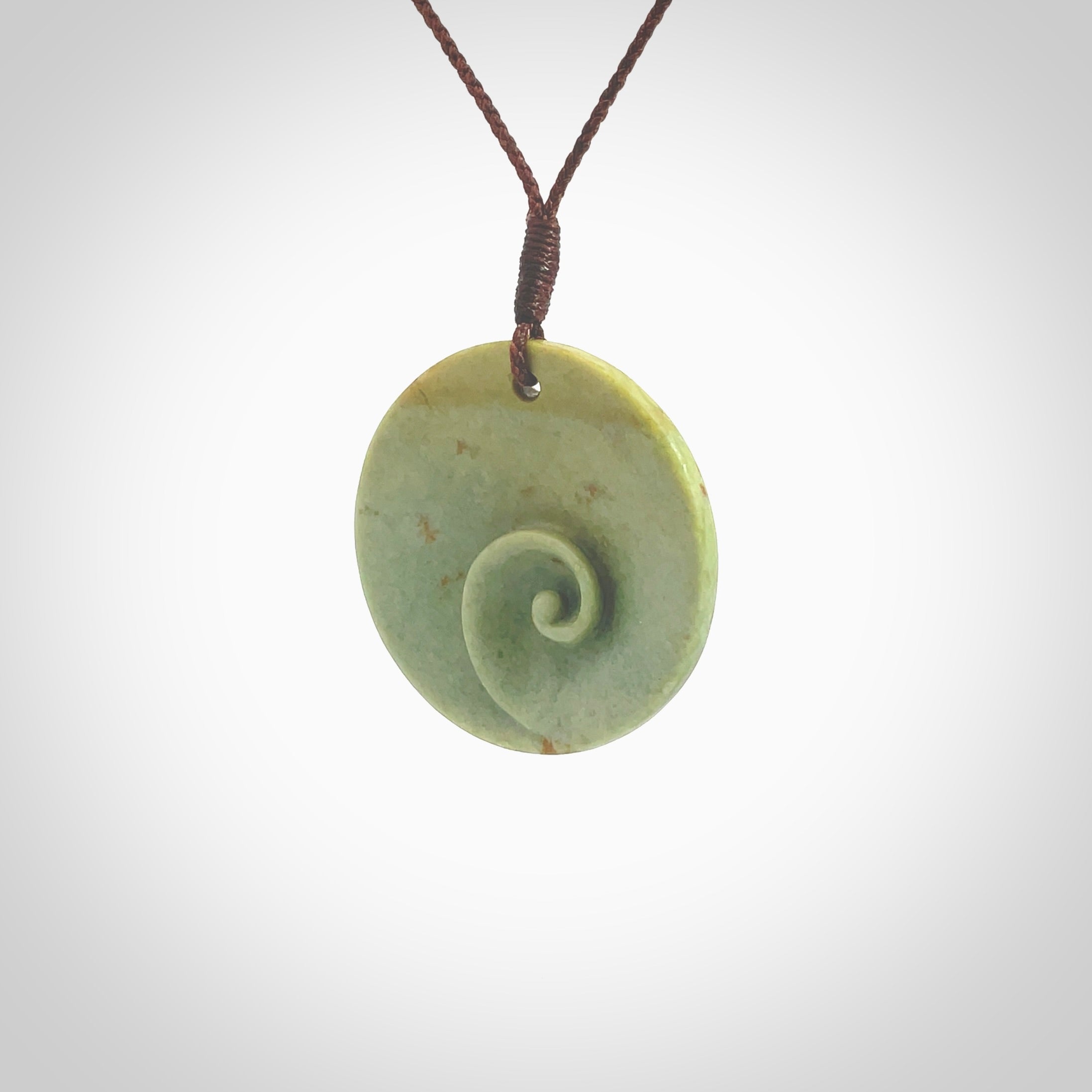 This pendant is a medium sized and cupped koru necklace carved from a lovely light green piece of New Zealand Marsden Flower Jade. Kyohei Noguchi carved this piece for us so the workmanship is outstanding. Handmade in New Zealand, a beautiful piece of jade jewellery. Provided with an adjustable brown cord and packaged in a woven kete pouch.