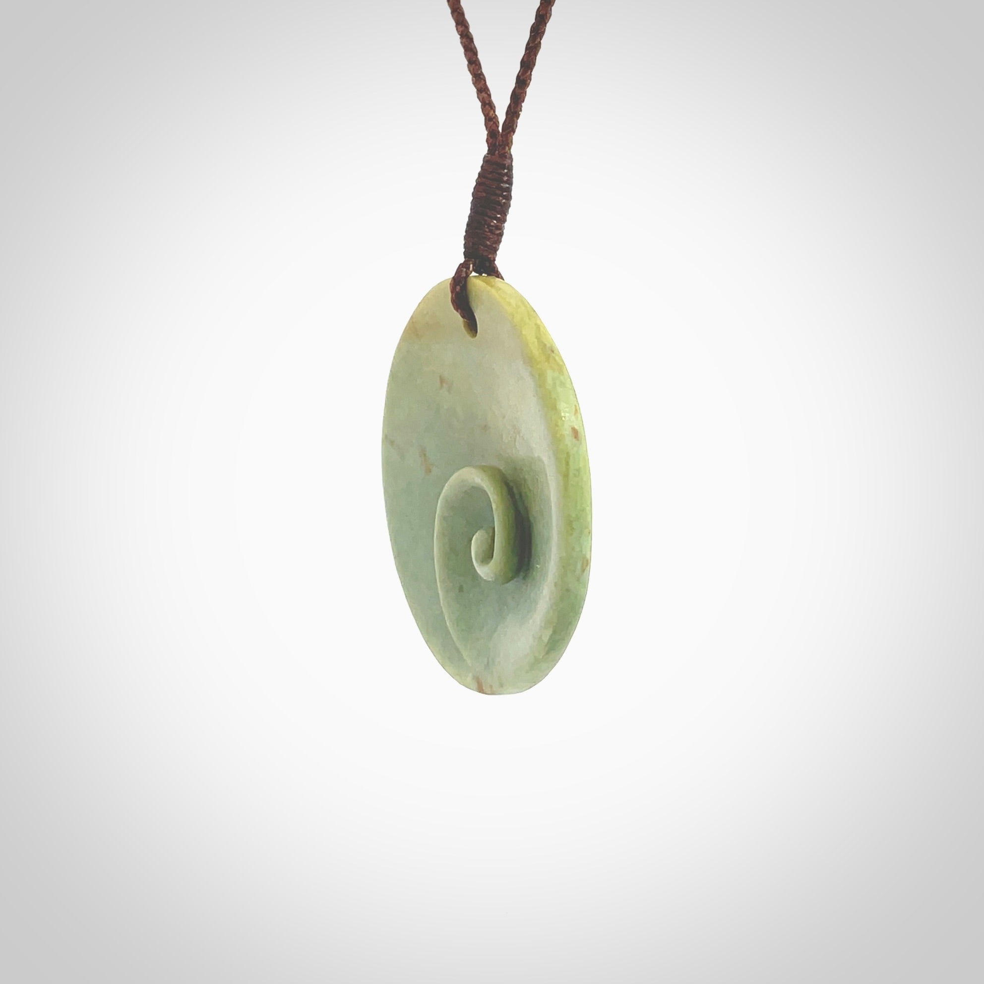 This pendant is a medium sized and cupped koru necklace carved from a lovely light green piece of New Zealand Marsden Flower Jade. Kyohei Noguchi carved this piece for us so the workmanship is outstanding. Handmade in New Zealand, a beautiful piece of jade jewellery. Provided with an adjustable brown cord and packaged in a woven kete pouch.