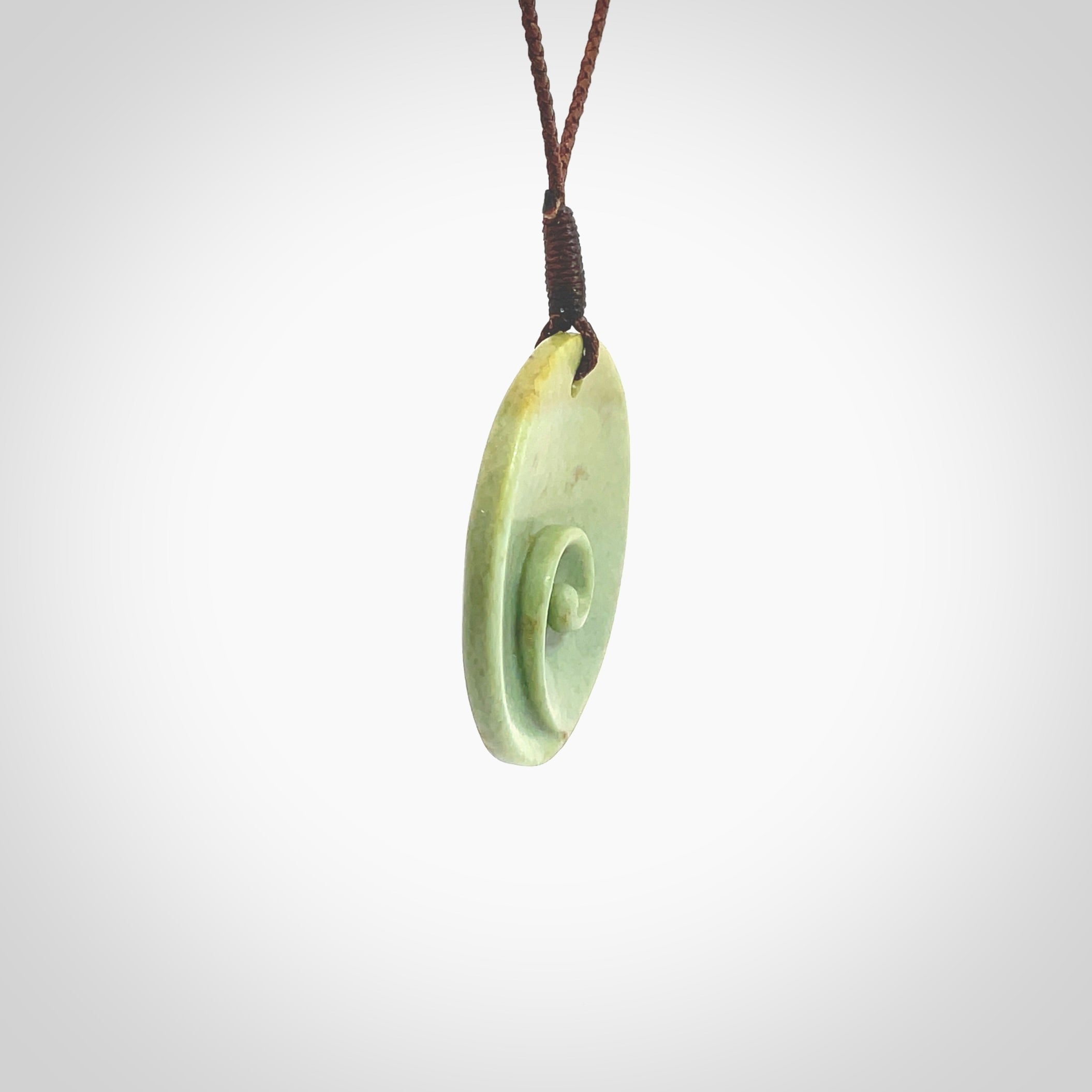 This pendant is a medium sized and cupped koru necklace carved from a lovely light green piece of New Zealand Marsden Flower Jade. Kyohei Noguchi carved this piece for us so the workmanship is outstanding. Handmade in New Zealand, a beautiful piece of jade jewellery. Provided with an adjustable brown cord and packaged in a woven kete pouch.