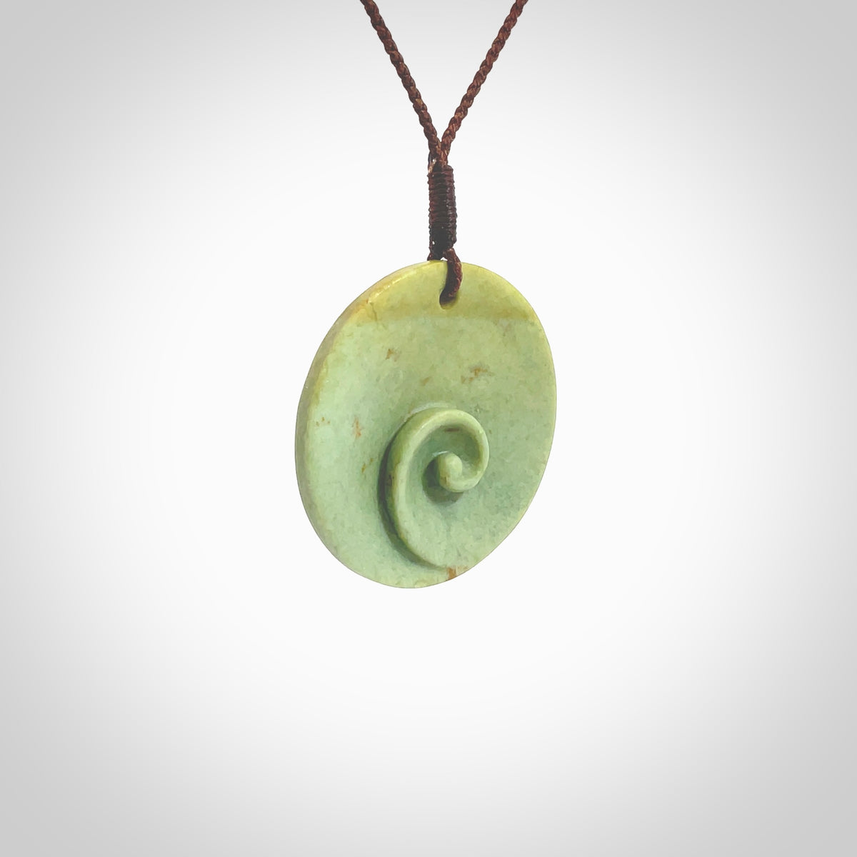 This pendant is a medium sized and cupped koru necklace carved from a lovely light green piece of New Zealand Marsden Flower Jade. Kyohei Noguchi carved this piece for us so the workmanship is outstanding. Handmade in New Zealand, a beautiful piece of jade jewellery. Provided with an adjustable brown cord and packaged in a woven kete pouch.