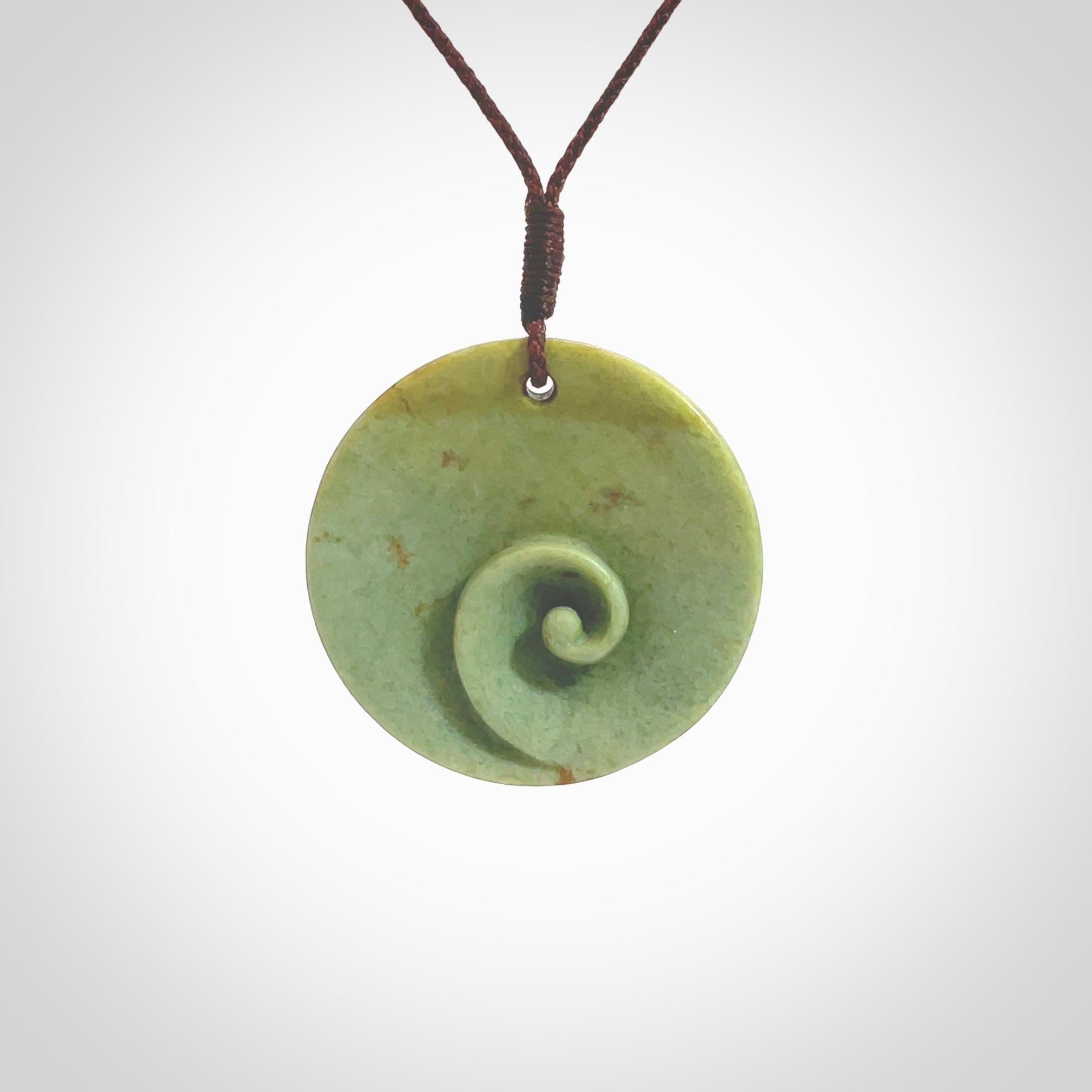 This pendant is a medium sized and cupped koru necklace carved from a lovely light green piece of New Zealand Marsden Flower Jade. Kyohei Noguchi carved this piece for us so the workmanship is outstanding. Handmade in New Zealand, a beautiful piece of jade jewellery. Provided with an adjustable brown cord and packaged in a woven kete pouch.