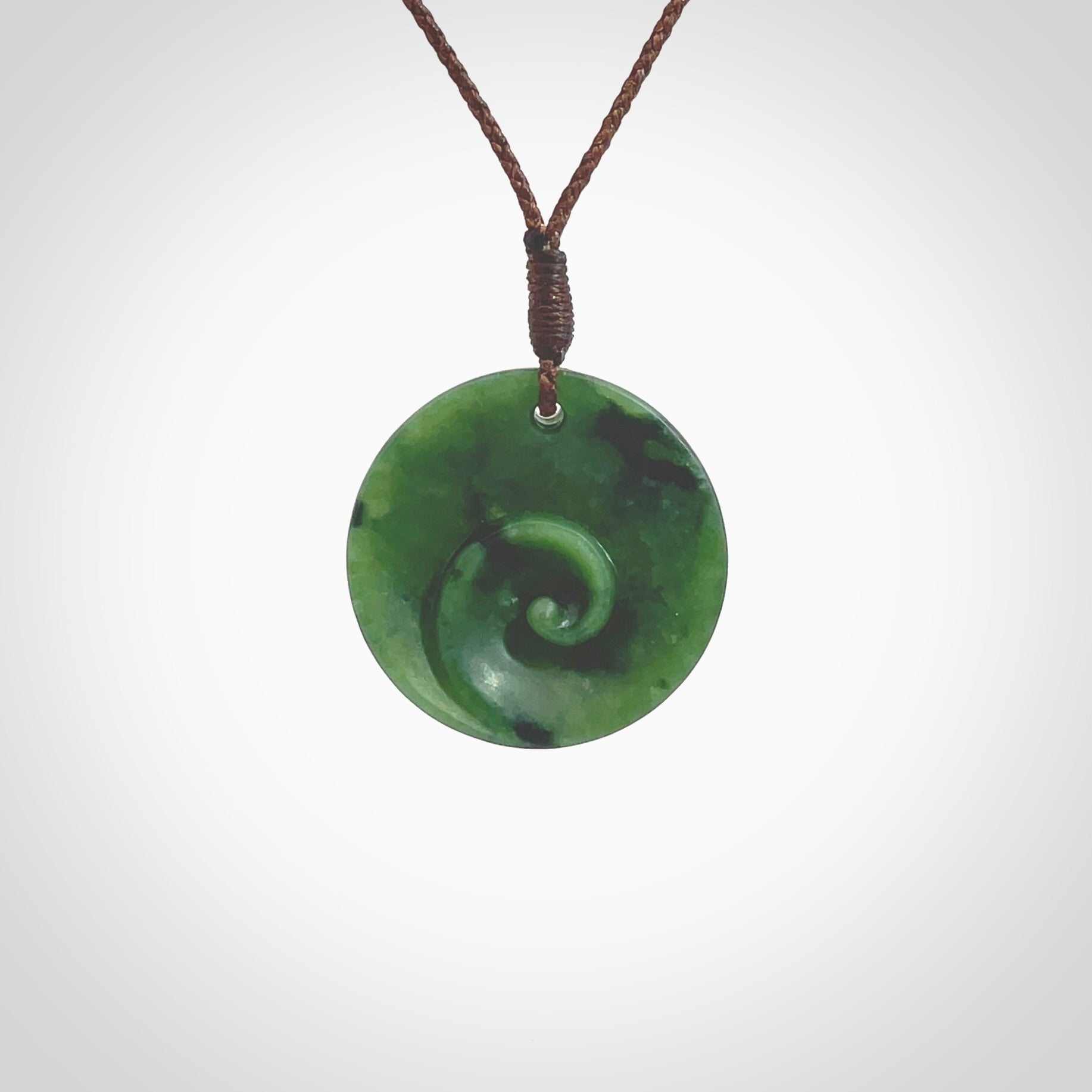 This pendant is a small sized and cupped koru necklace carved from a dark green piece of New Zealand Marsden Jade. Kyohei Noguchi carved this piece for us so the workmanship is outstanding. Handmade in New Zealand, a beautiful piece of jade jewellery. Provided with an adjustable brown cord and packaged in a woven kete pouch.