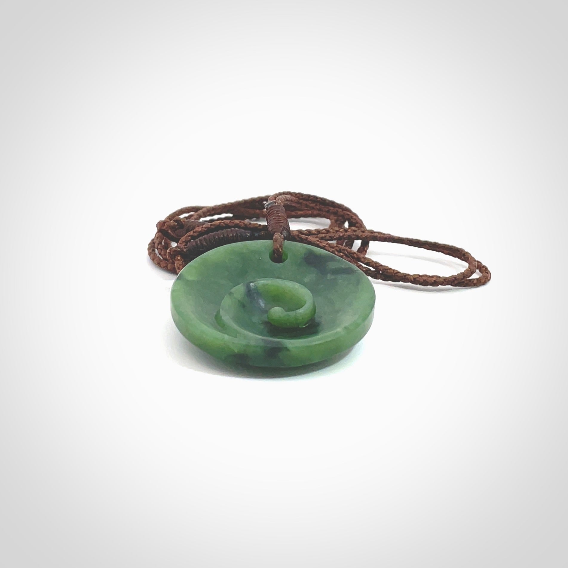 This pendant is a small sized and cupped koru necklace carved from a dark green piece of New Zealand Marsden Jade. Kyohei Noguchi carved this piece for us so the workmanship is outstanding. Handmade in New Zealand, a beautiful piece of jade jewellery. Provided with an adjustable brown cord and packaged in a woven kete pouch.