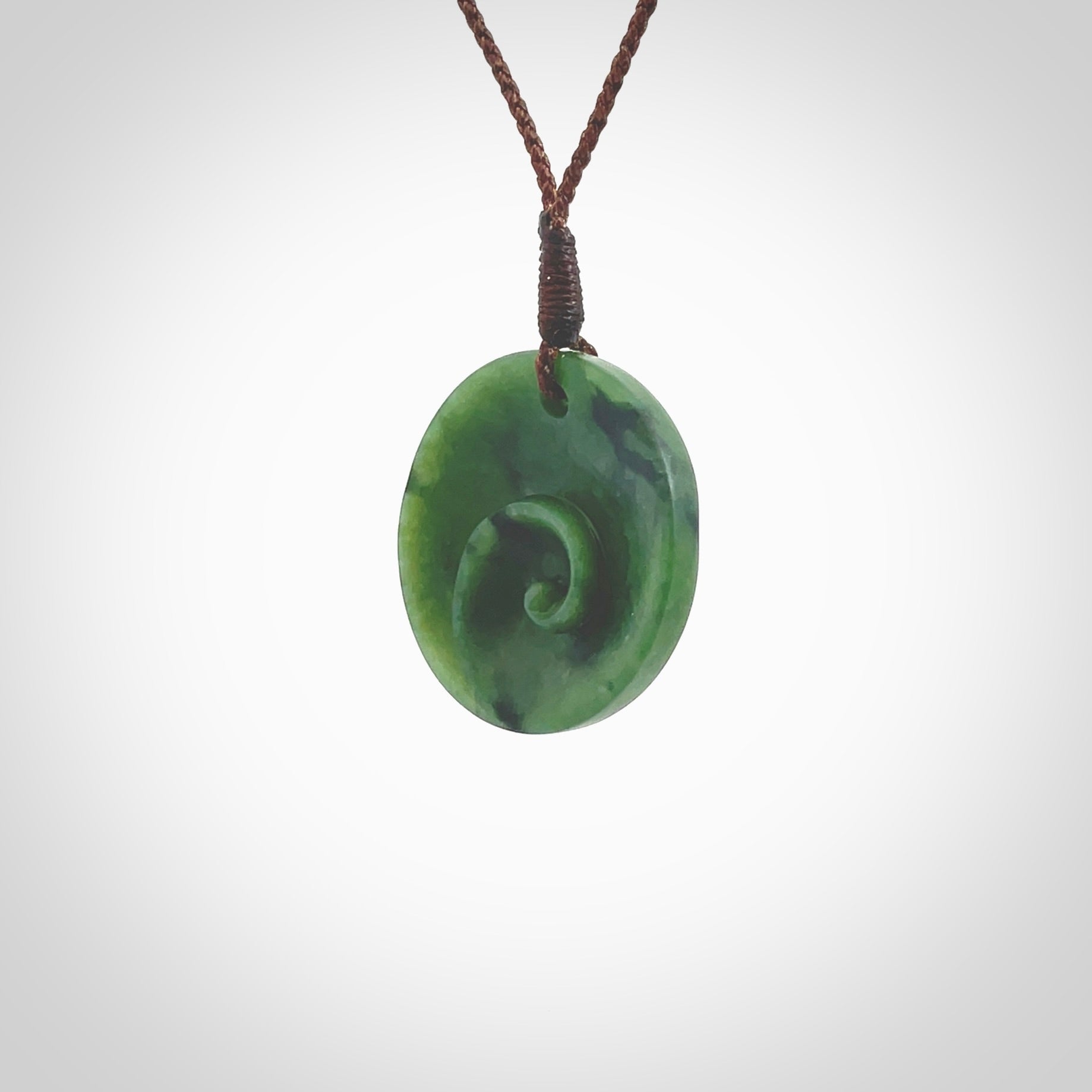 This pendant is a small sized and cupped koru necklace carved from a dark green piece of New Zealand Marsden Jade. Kyohei Noguchi carved this piece for us so the workmanship is outstanding. Handmade in New Zealand, a beautiful piece of jade jewellery. Provided with an adjustable brown cord and packaged in a woven kete pouch.