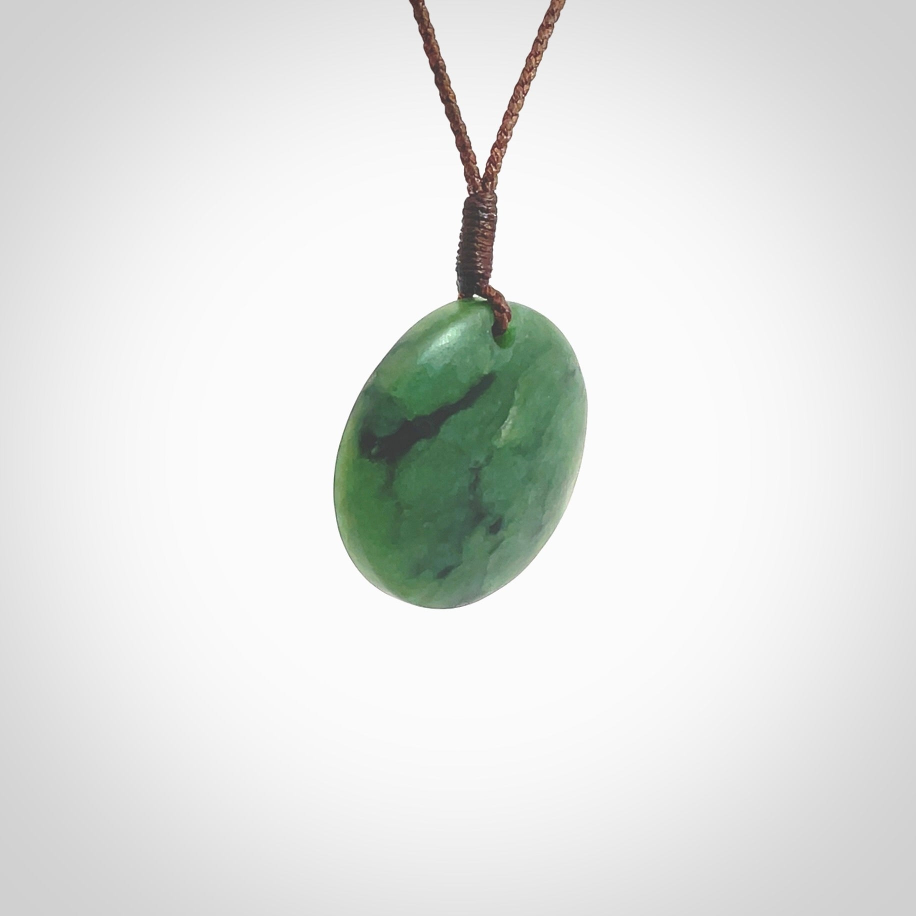 This pendant is a small sized and cupped koru necklace carved from a dark green piece of New Zealand Marsden Jade. Kyohei Noguchi carved this piece for us so the workmanship is outstanding. Handmade in New Zealand, a beautiful piece of jade jewellery. Provided with an adjustable brown cord and packaged in a woven kete pouch.