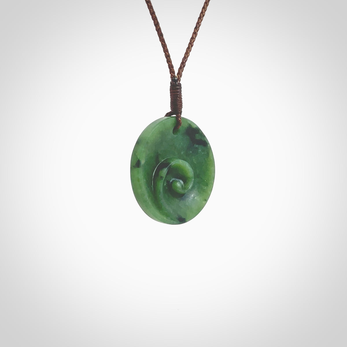 This pendant is a small sized and cupped koru necklace carved from a dark green piece of New Zealand Marsden Jade. Kyohei Noguchi carved this piece for us so the workmanship is outstanding. Handmade in New Zealand, a beautiful piece of jade jewellery. Provided with an adjustable brown cord and packaged in a woven kete pouch.