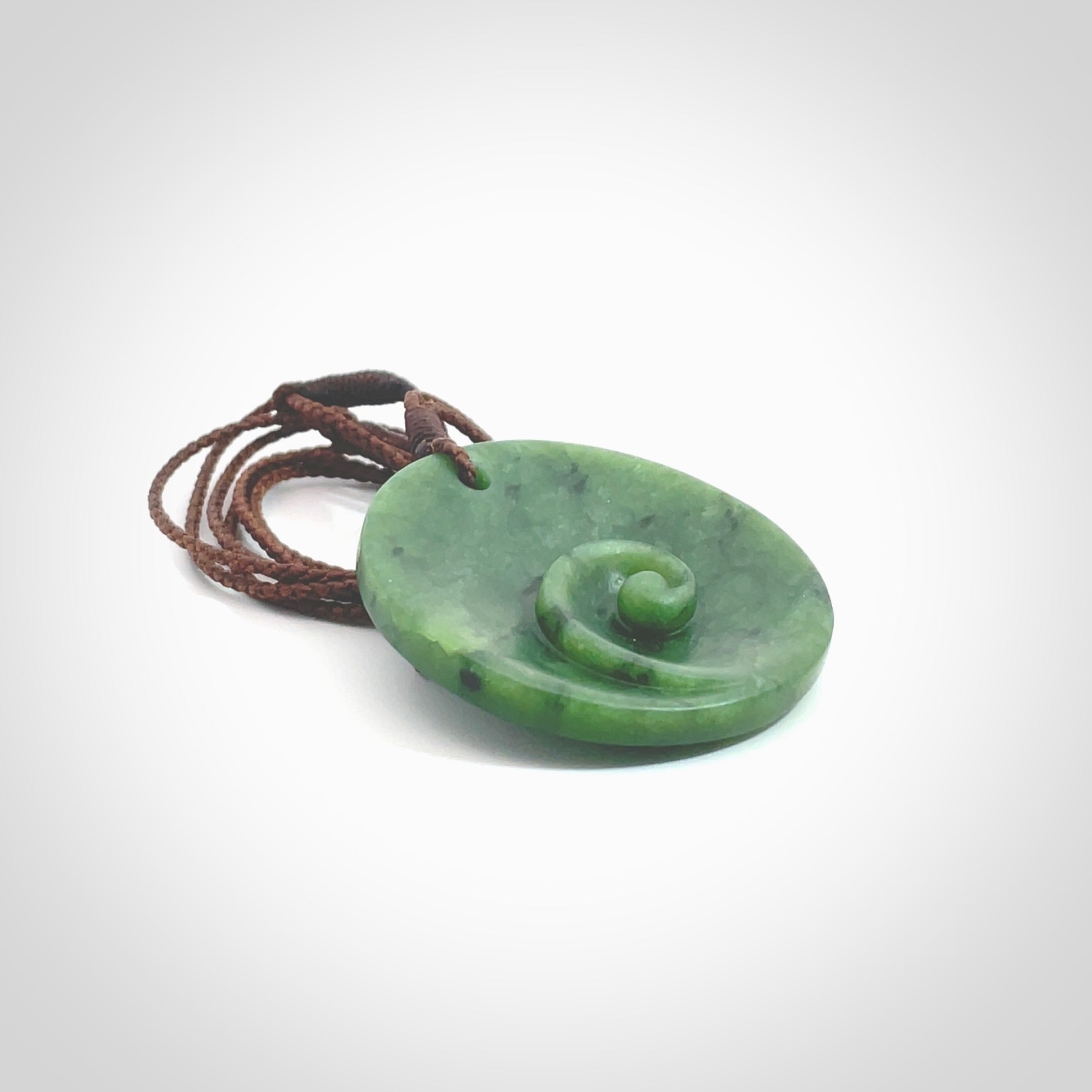 This pendant is a medium sized and cupped koru necklace carved from a lovely piece of New Zealand Jade. Kyohei Noguchi carved this piece for us so the workmanship is outstanding. Handmade in New Zealand, a beautiful piece of jade jewellery. Provided with an adjustable brown cord and packaged in a woven kete pouch.