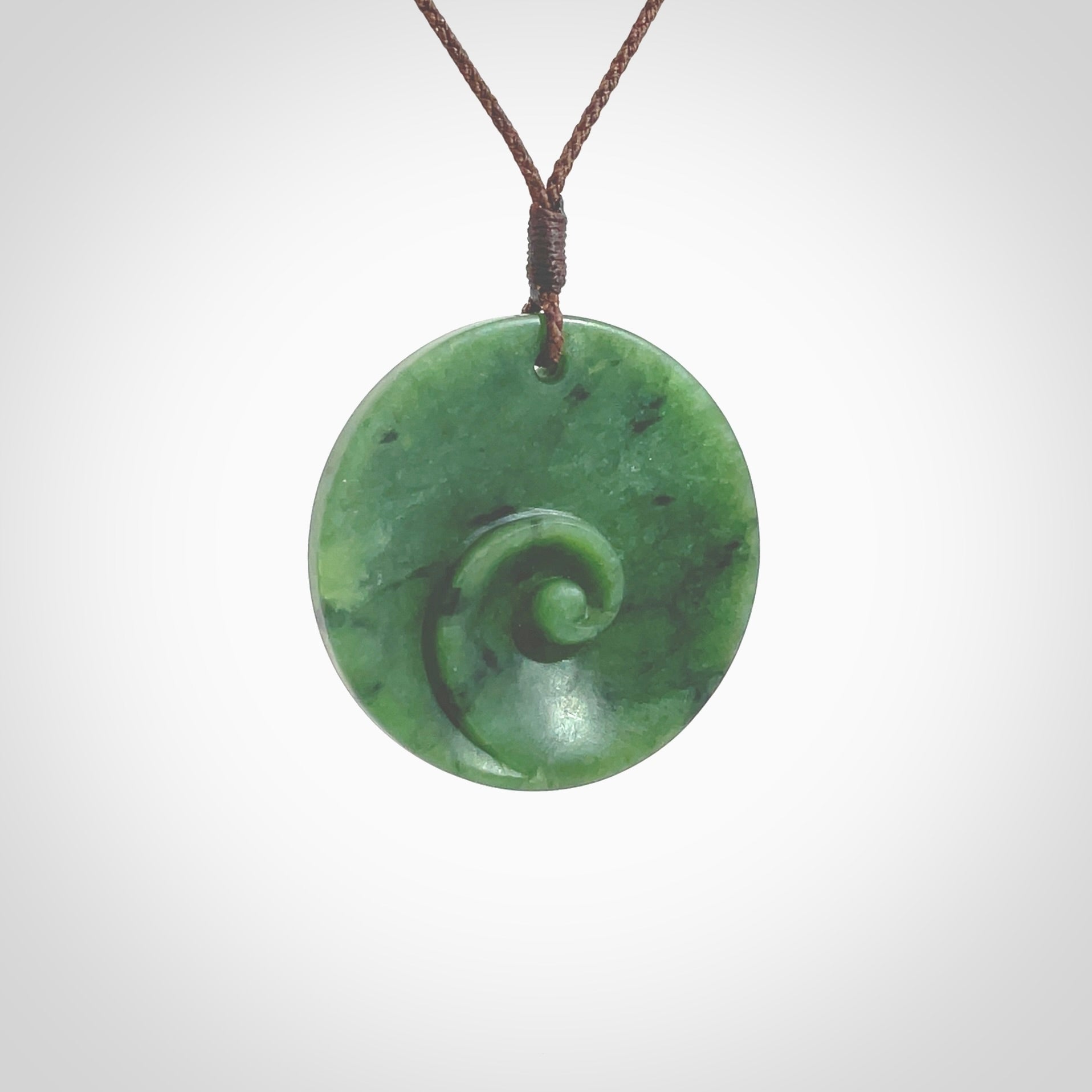 This pendant is a medium sized and cupped koru necklace carved from a lovely piece of New Zealand Jade. Kyohei Noguchi carved this piece for us so the workmanship is outstanding. Handmade in New Zealand, a beautiful piece of jade jewellery. Provided with an adjustable brown cord and packaged in a woven kete pouch.