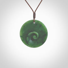 This pendant is a medium sized and cupped koru necklace carved from a lovely piece of New Zealand Jade. Kyohei Noguchi carved this piece for us so the workmanship is outstanding. Handmade in New Zealand, a beautiful piece of jade jewellery. Provided with an adjustable brown cord and packaged in a woven kete pouch.