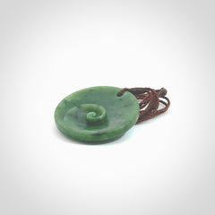 This pendant is a medium sized and cupped koru necklace carved from a lovely piece of New Zealand Jade. Kyohei Noguchi carved this piece for us so the workmanship is outstanding. Handmade in New Zealand, a beautiful piece of jade jewellery. Provided with an adjustable brown cord and packaged in a woven kete pouch.