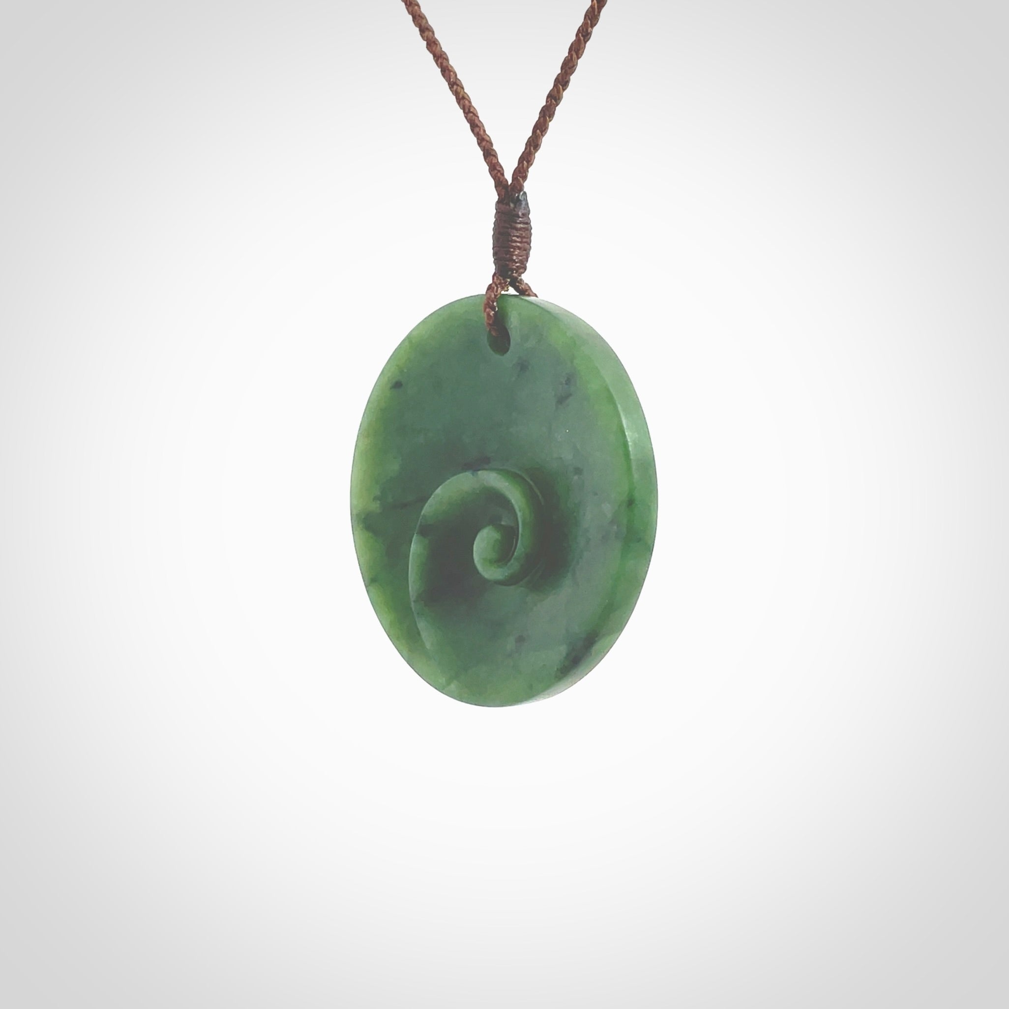 This pendant is a medium sized and cupped koru necklace carved from a lovely piece of New Zealand Jade. Kyohei Noguchi carved this piece for us so the workmanship is outstanding. Handmade in New Zealand, a beautiful piece of jade jewellery. Provided with an adjustable brown cord and packaged in a woven kete pouch.