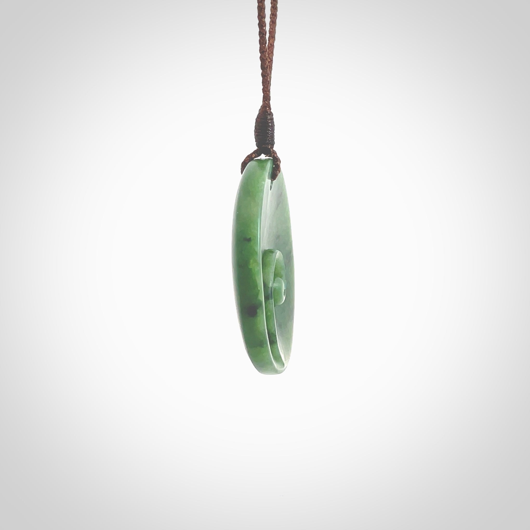 This pendant is a medium sized and cupped koru necklace carved from a lovely piece of New Zealand Jade. Kyohei Noguchi carved this piece for us so the workmanship is outstanding. Handmade in New Zealand, a beautiful piece of jade jewellery. Provided with an adjustable brown cord and packaged in a woven kete pouch.