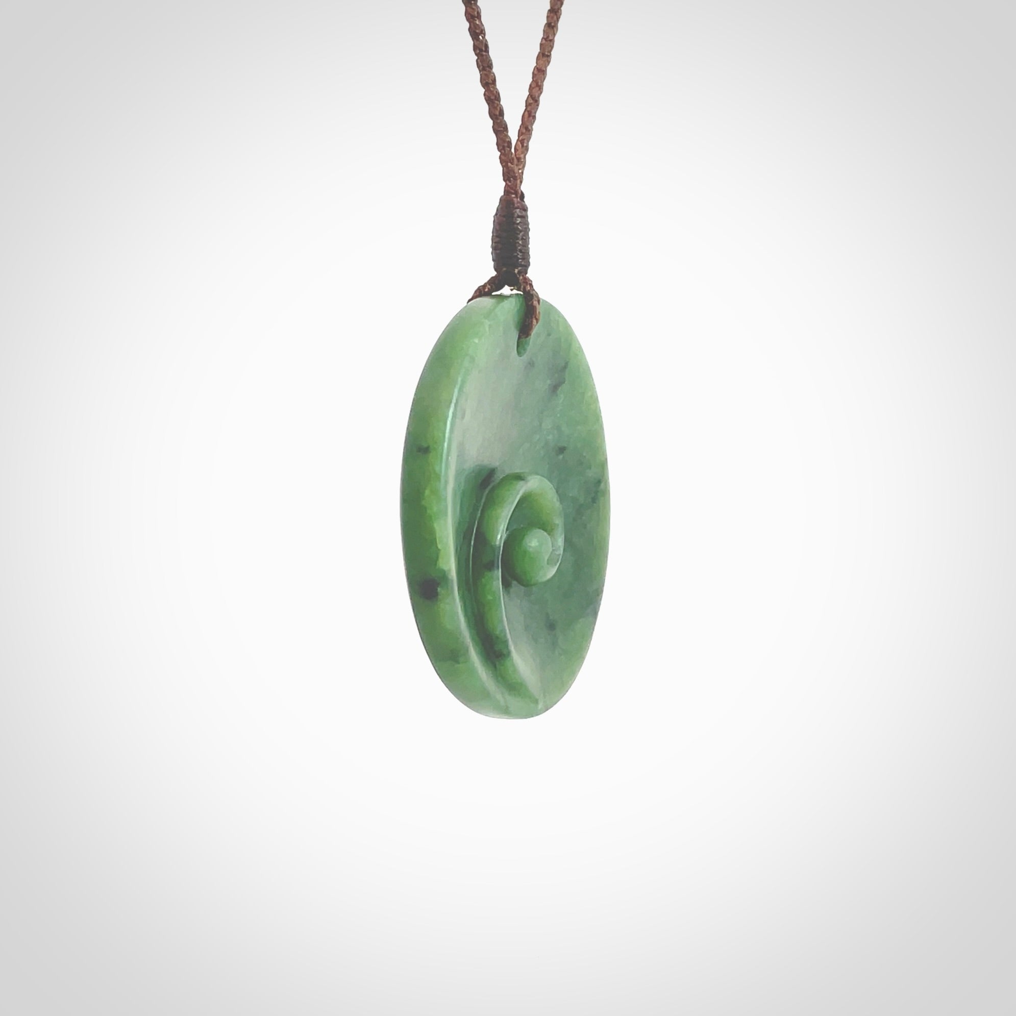 This pendant is a medium sized and cupped koru necklace carved from a lovely piece of New Zealand Jade. Kyohei Noguchi carved this piece for us so the workmanship is outstanding. Handmade in New Zealand, a beautiful piece of jade jewellery. Provided with an adjustable brown cord and packaged in a woven kete pouch.