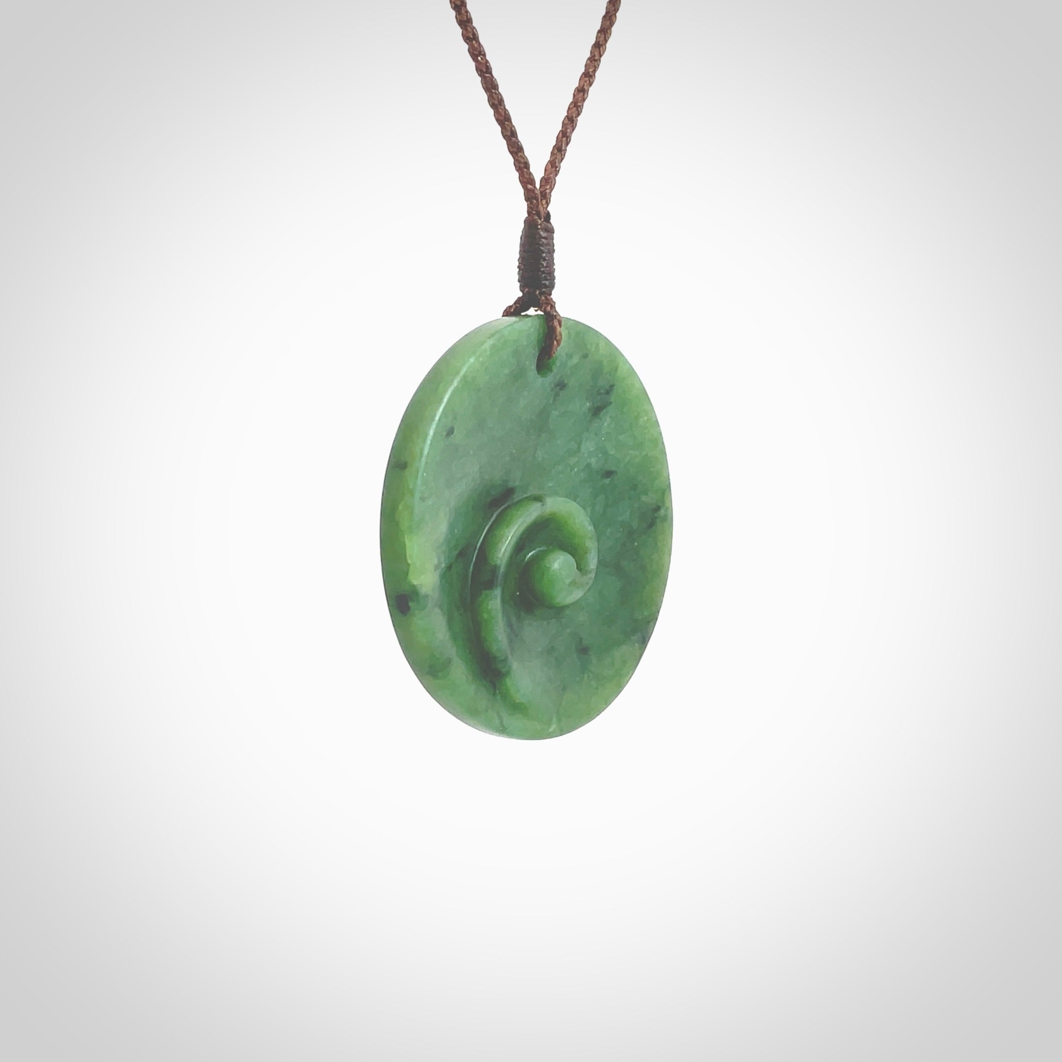 This pendant is a medium sized and cupped koru necklace carved from a lovely piece of New Zealand Jade. Kyohei Noguchi carved this piece for us so the workmanship is outstanding. Handmade in New Zealand, a beautiful piece of jade jewellery. Provided with an adjustable brown cord and packaged in a woven kete pouch.