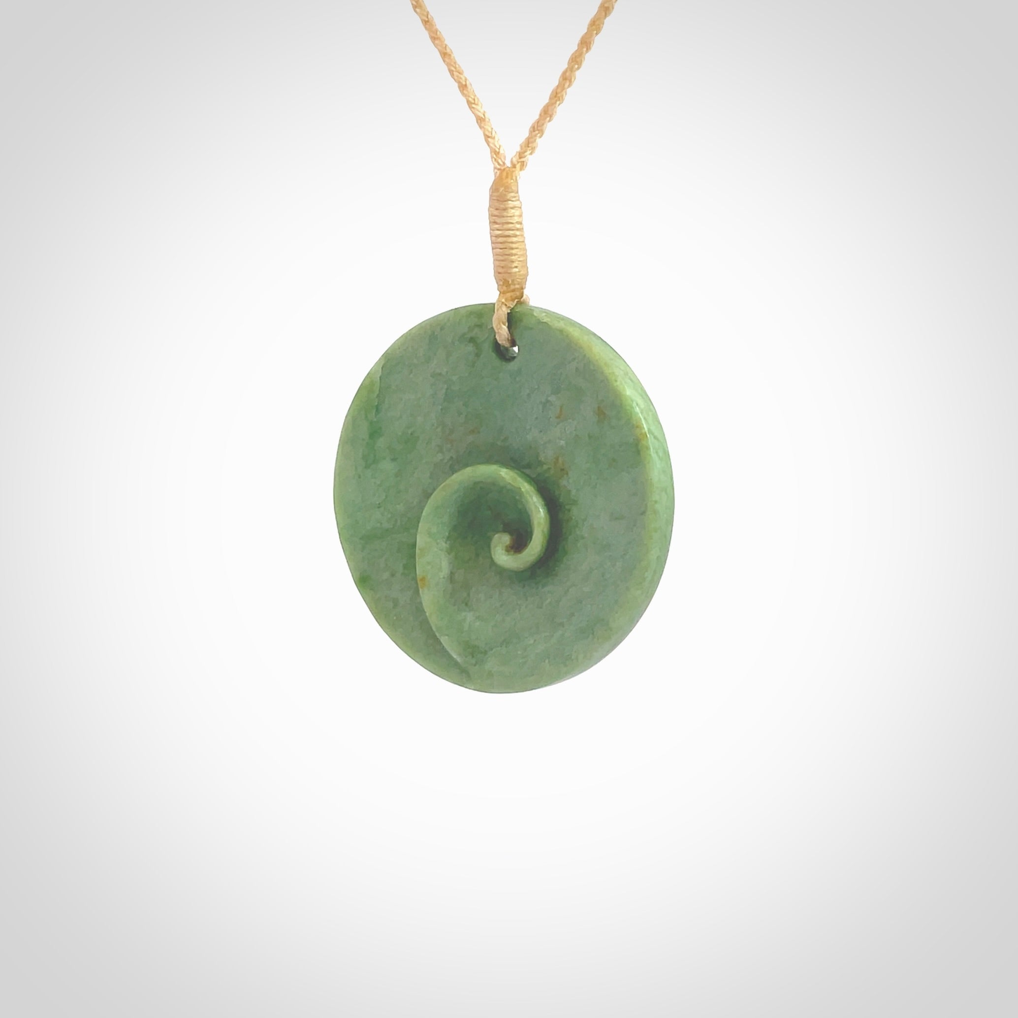 This pendant is a medium sized and cupped koru necklace carved from a lovely light green piece of New Zealand Marsden Flower Jade. Kyohei Noguchi carved this piece for us so the workmanship is outstanding. Handmade in New Zealand, a beautiful piece of jade jewellery. Provided with an adjustable beige cord and packaged in a woven kete pouch.