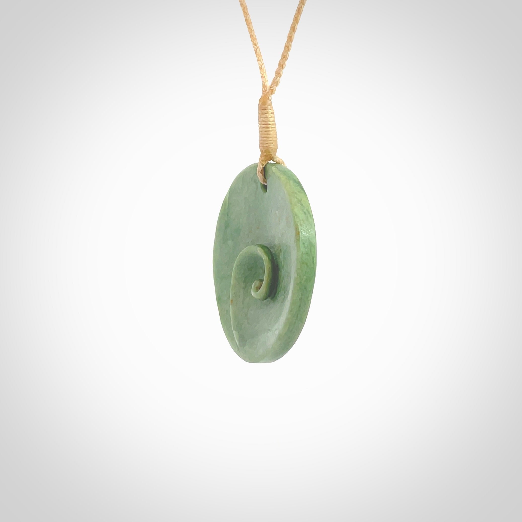 This pendant is a medium sized and cupped koru necklace carved from a lovely light green piece of New Zealand Marsden Flower Jade. Kyohei Noguchi carved this piece for us so the workmanship is outstanding. Handmade in New Zealand, a beautiful piece of jade jewellery. Provided with an adjustable beige cord and packaged in a woven kete pouch.