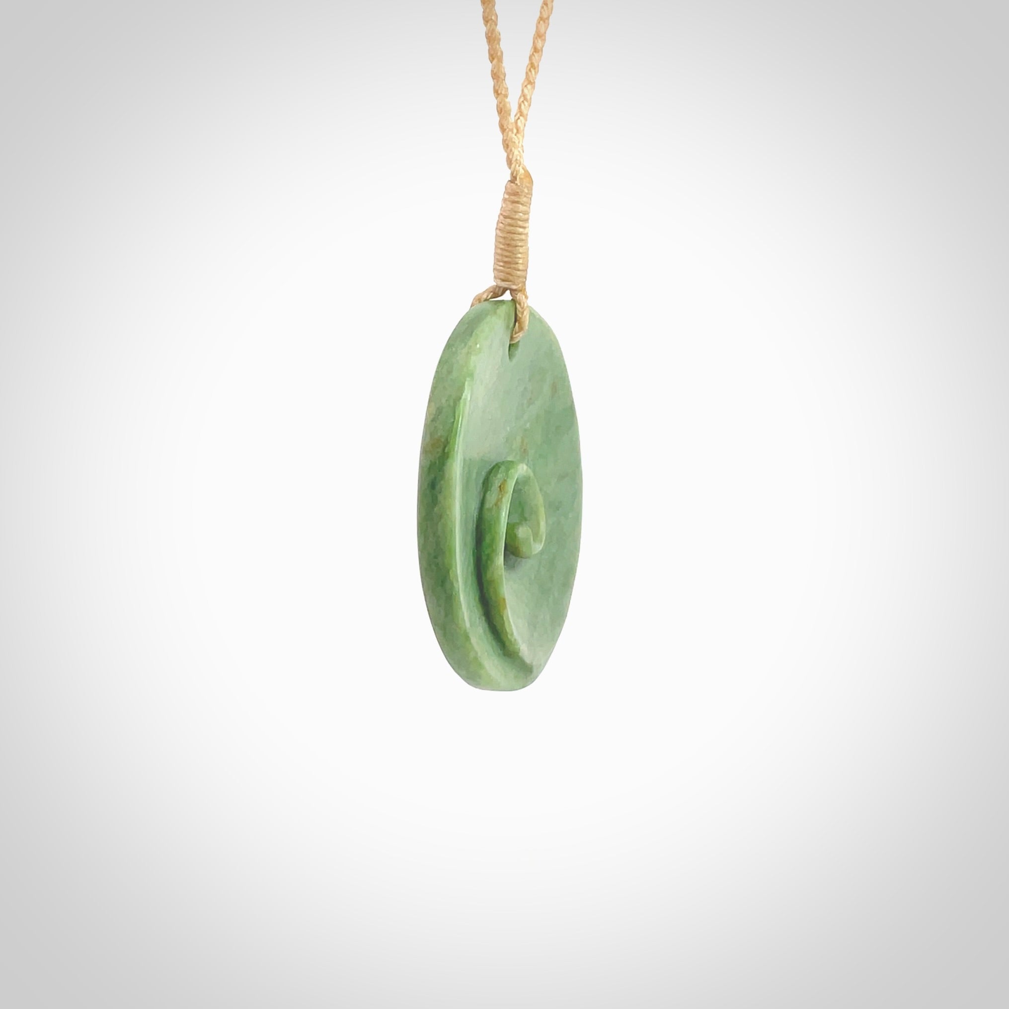 This pendant is a medium sized and cupped koru necklace carved from a lovely light green piece of New Zealand Marsden Flower Jade. Kyohei Noguchi carved this piece for us so the workmanship is outstanding. Handmade in New Zealand, a beautiful piece of jade jewellery. Provided with an adjustable beige cord and packaged in a woven kete pouch.