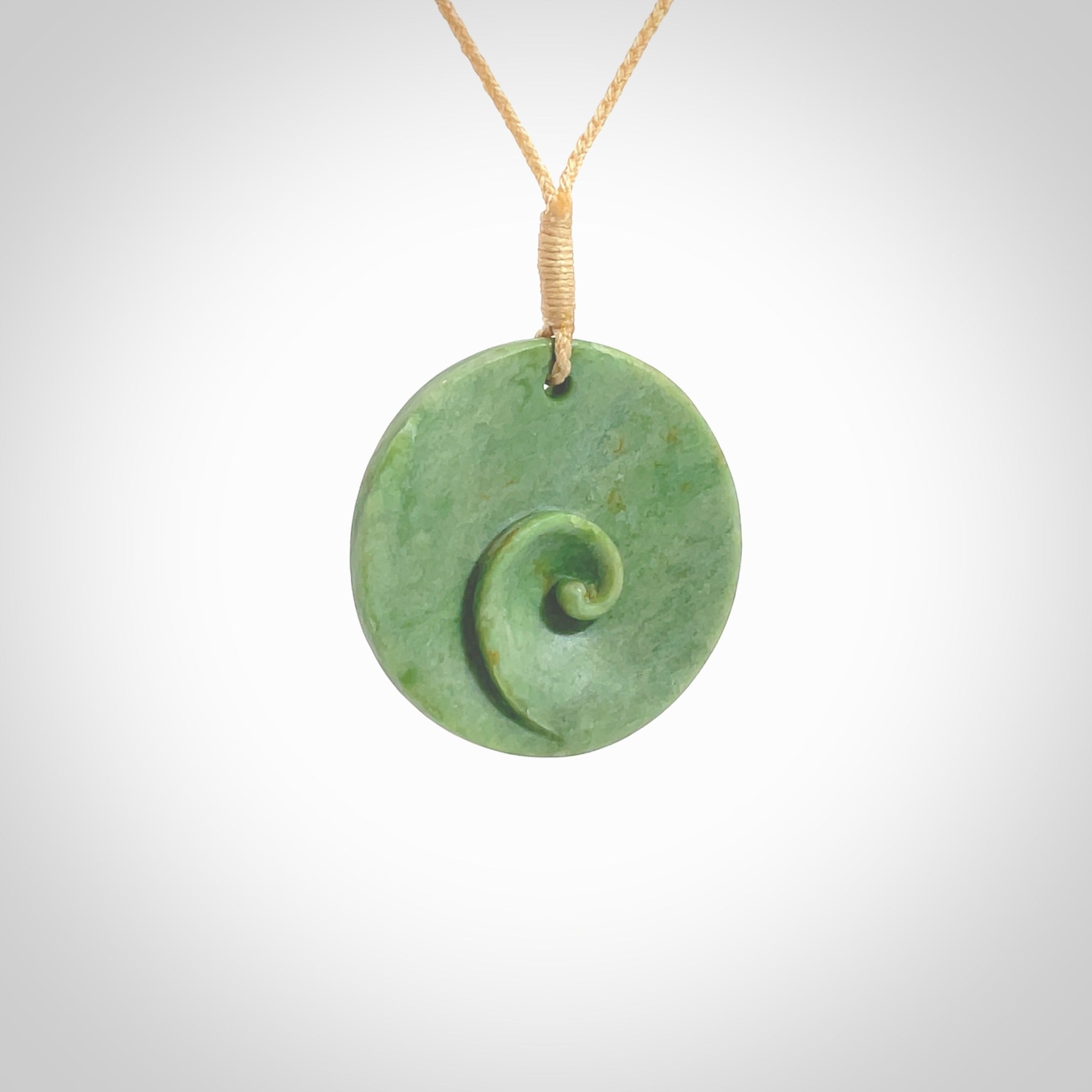 This pendant is a medium sized and cupped koru necklace carved from a lovely light green piece of New Zealand Marsden Flower Jade. Kyohei Noguchi carved this piece for us so the workmanship is outstanding. Handmade in New Zealand, a beautiful piece of jade jewellery. Provided with an adjustable beige cord and packaged in a woven kete pouch.