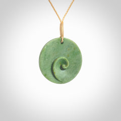 This pendant is a medium sized and cupped koru necklace carved from a lovely light green piece of New Zealand Marsden Flower Jade. Kyohei Noguchi carved this piece for us so the workmanship is outstanding. Handmade in New Zealand, a beautiful piece of jade jewellery. Provided with an adjustable beige cord and packaged in a woven kete pouch.