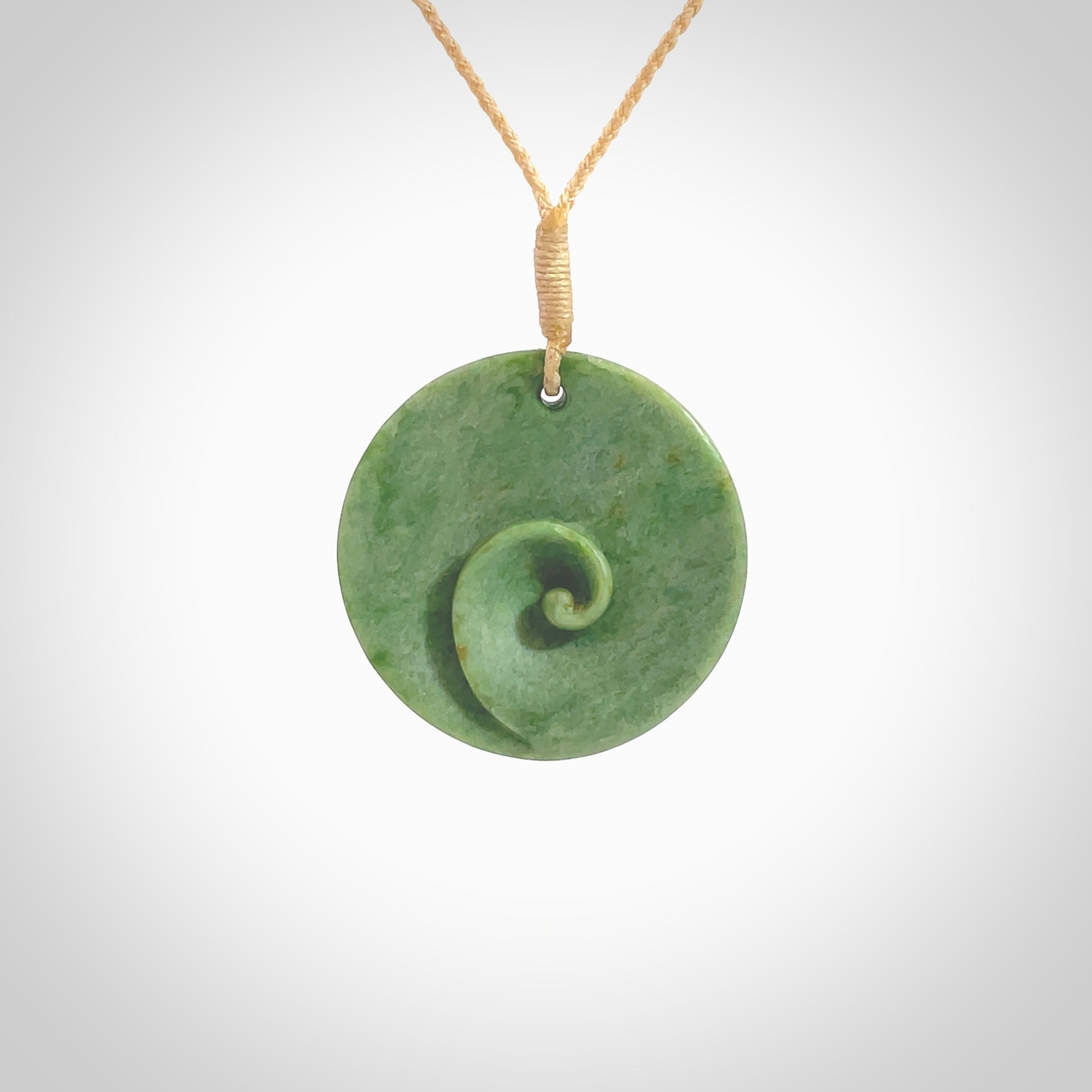 This pendant is a medium sized and cupped koru necklace carved from a lovely light green piece of New Zealand Marsden Flower Jade. Kyohei Noguchi carved this piece for us so the workmanship is outstanding. Handmade in New Zealand, a beautiful piece of jade jewellery. Provided with an adjustable beige cord and packaged in a woven kete pouch.